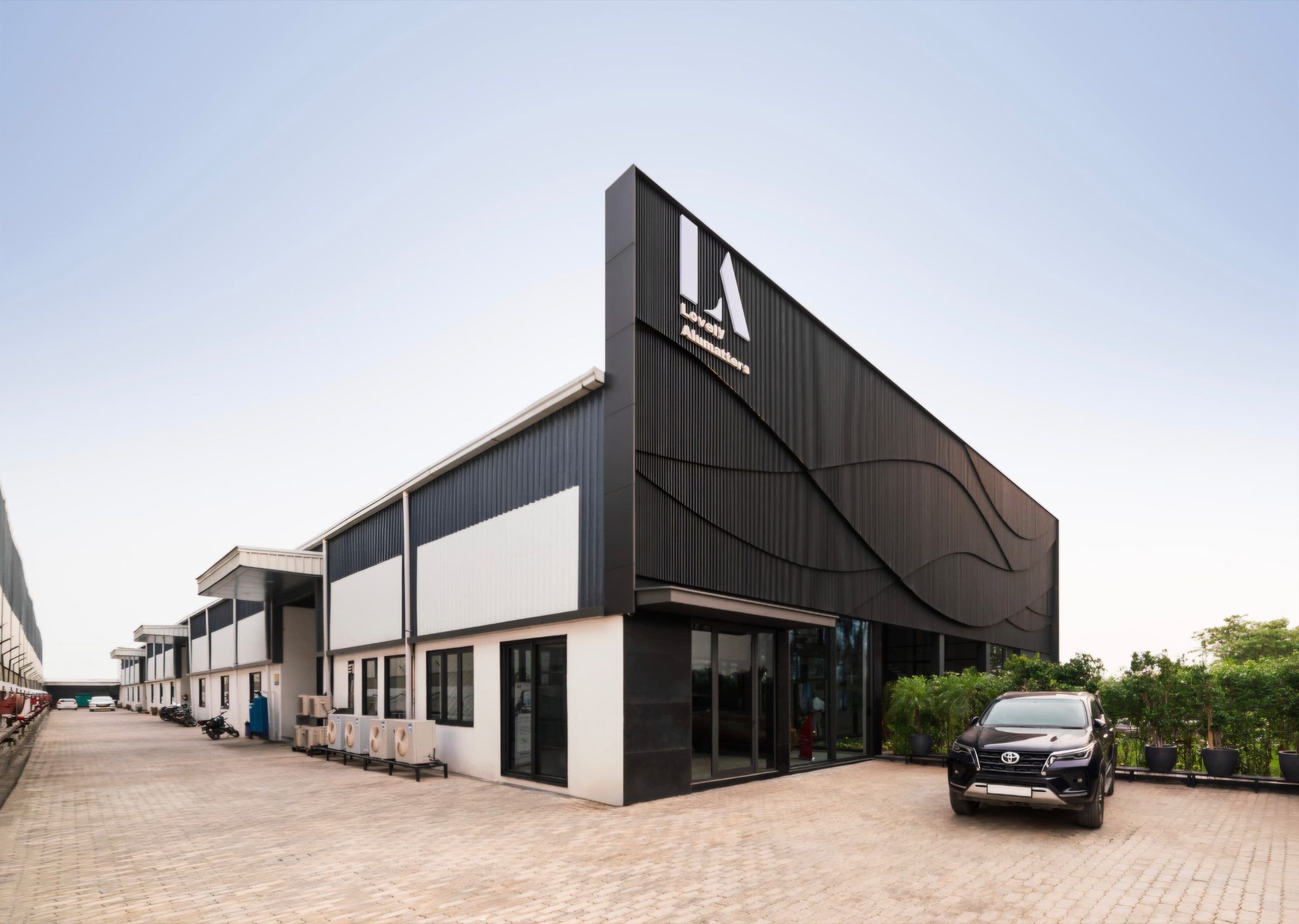 Dark ribbed façade of the facility with glazed entrances in daylight
