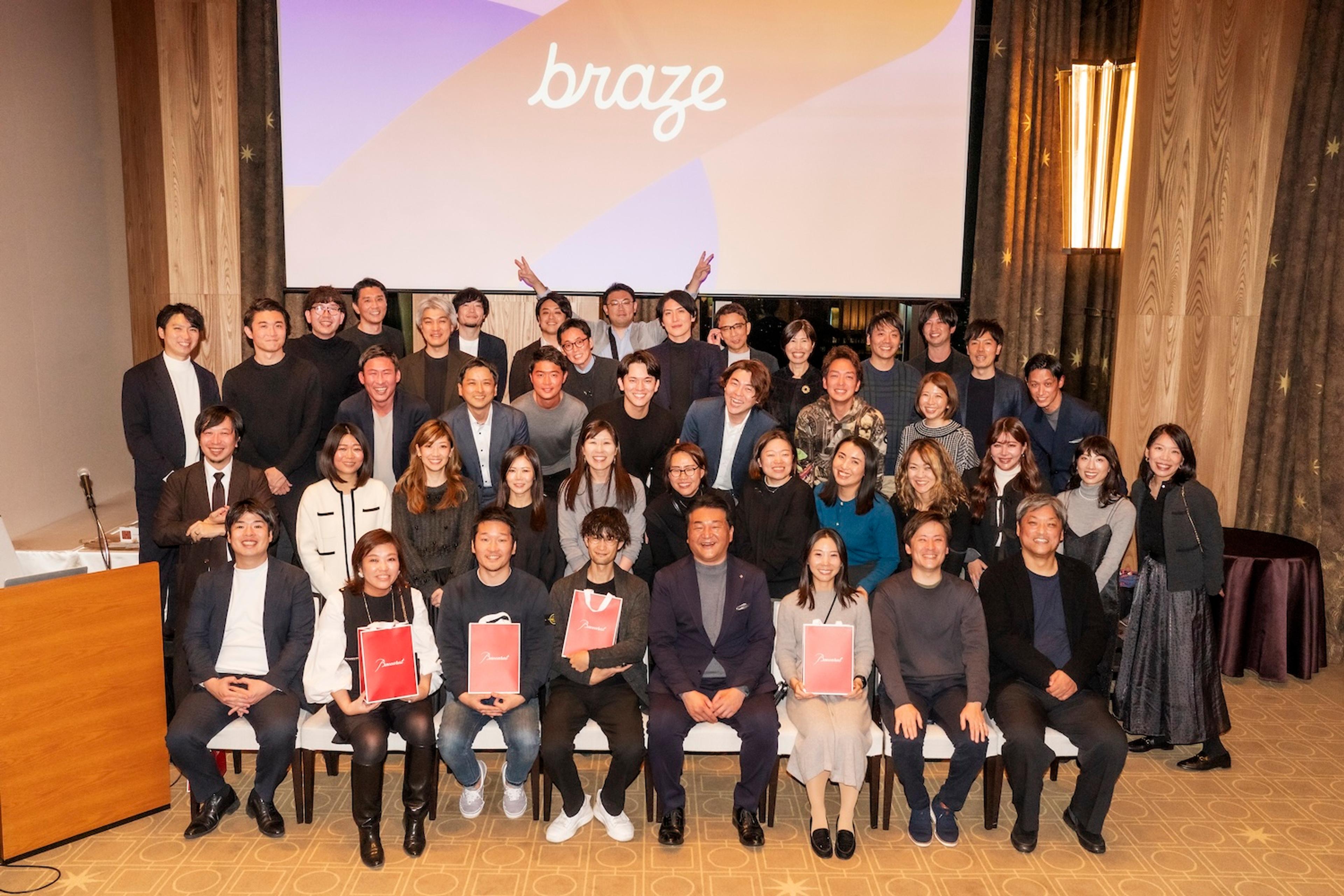 a large group of people are posing for a picture in front of a large screen .