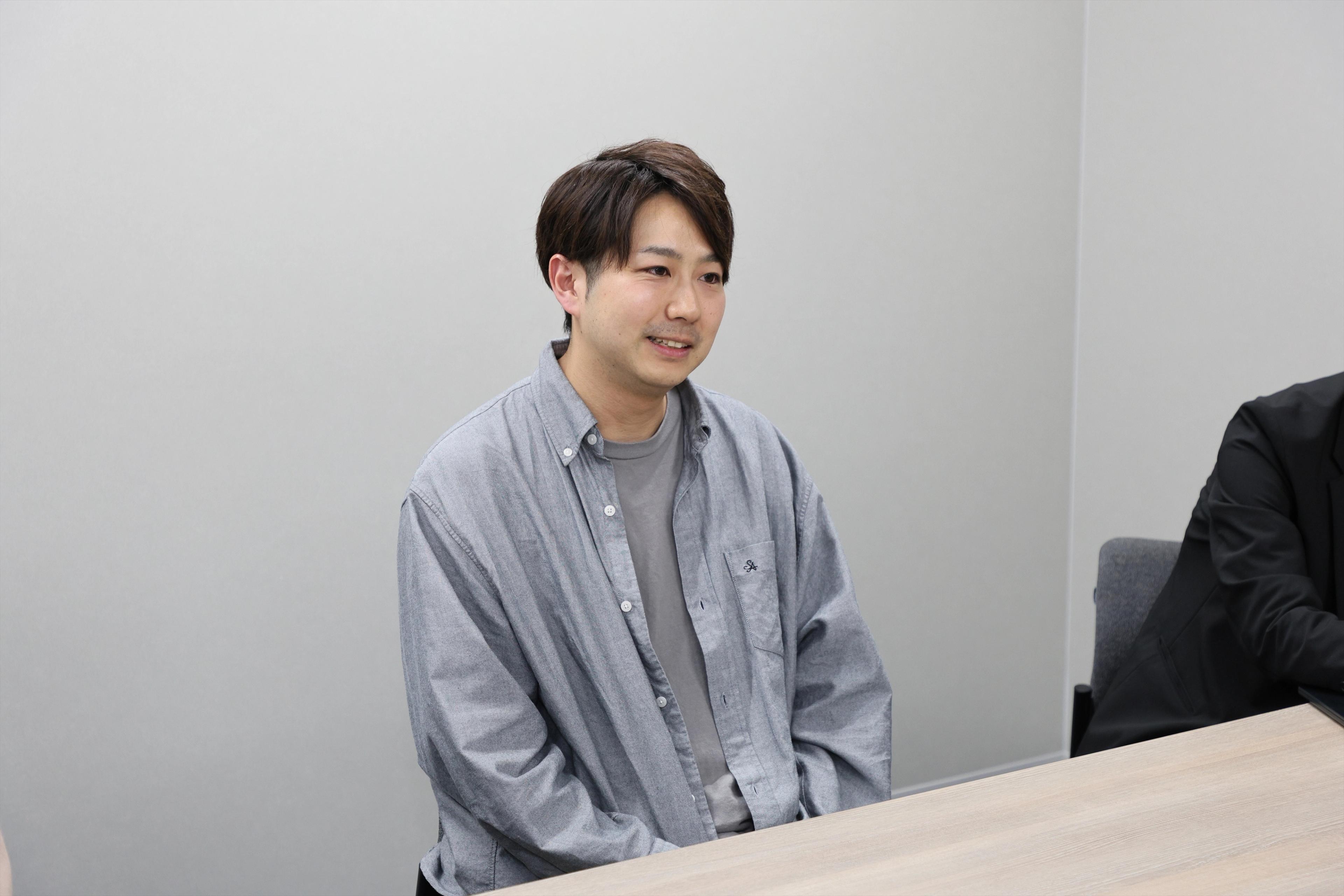 OMO本部マーケティング部マネジャー 白倉 鉄平氏がインタビューを受けている様子。グレーシャツをきていて笑顔で話をしている
