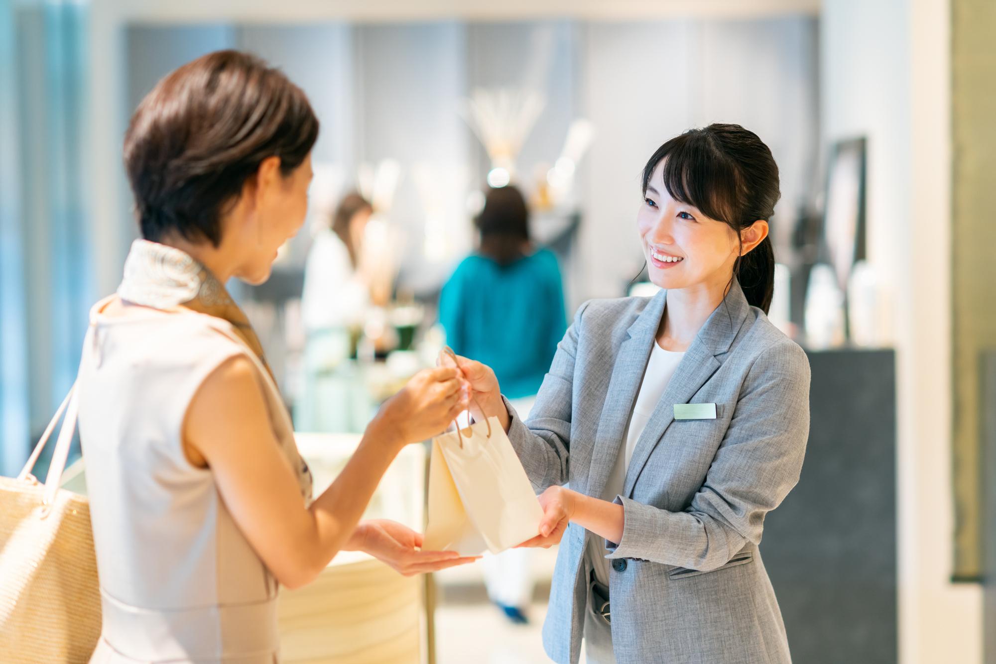 店員が顧客に小さな袋を渡しているシーン。明るい店内でのやり取り。