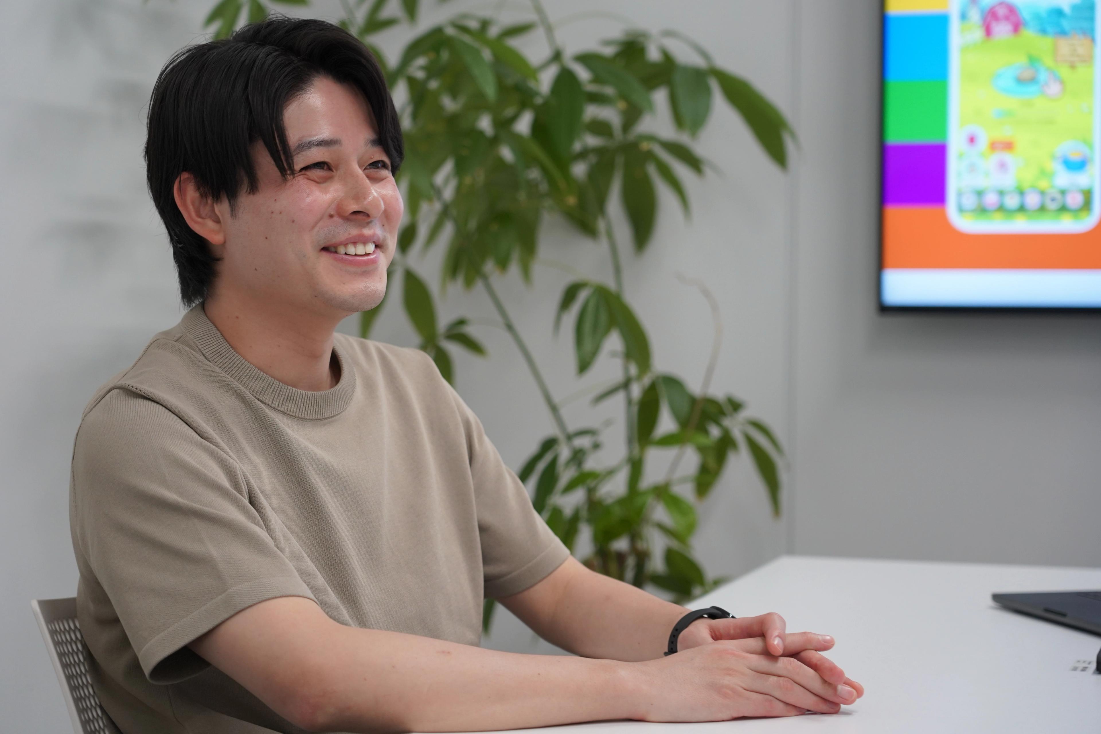 男性が座って笑顔でインタビューに応えている