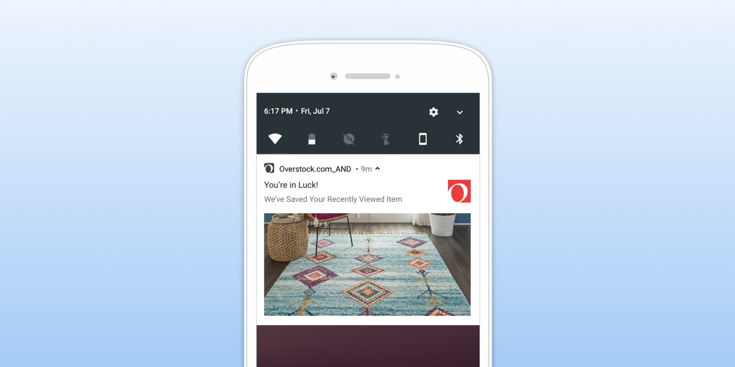 A smartphone screen displaying a notification from Overstock.com about a recently viewed item, featuring a colorful area rug. The background is a gradient of light blue.
