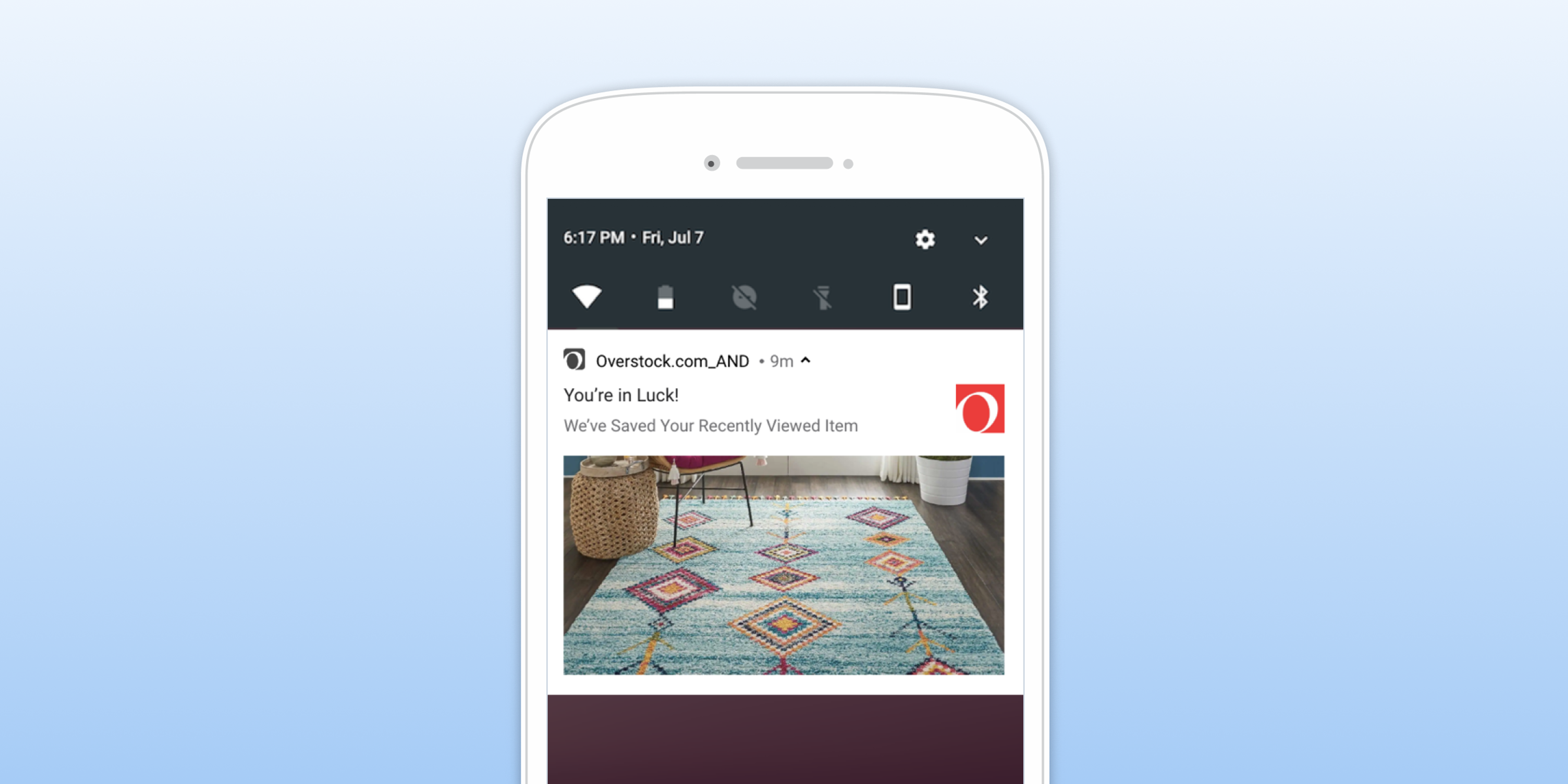 A smartphone screen displaying a notification from Overstock.com about a recently viewed item, featuring a colorful area rug. The background is a gradient of light blue.