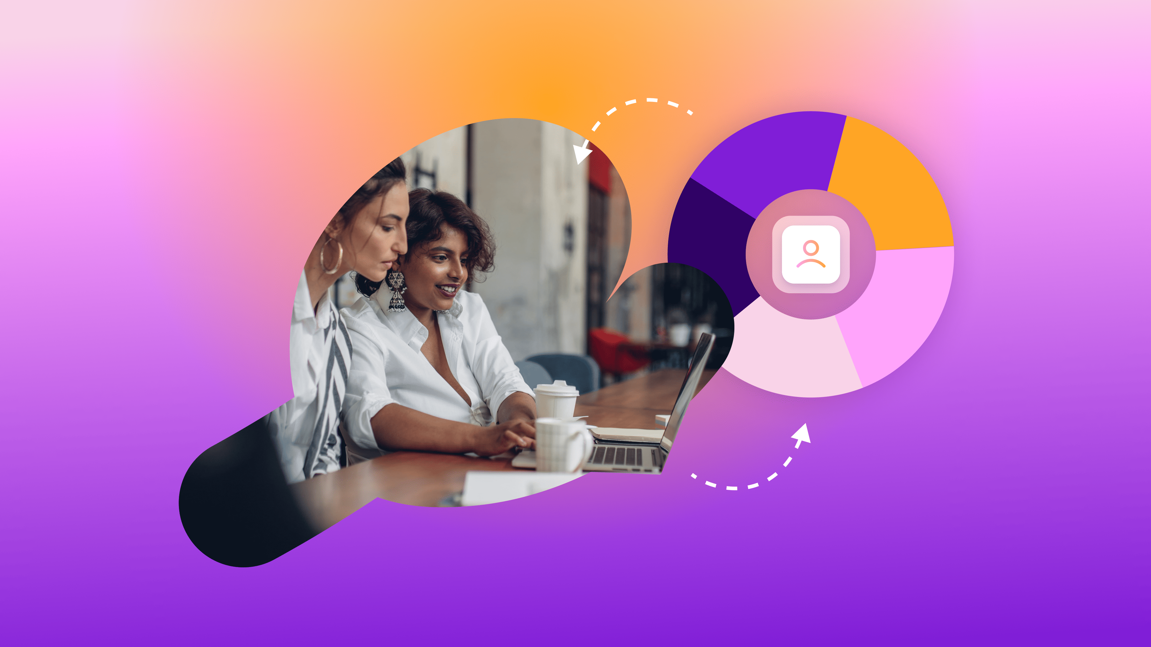 two women sit at a table looking at a laptop