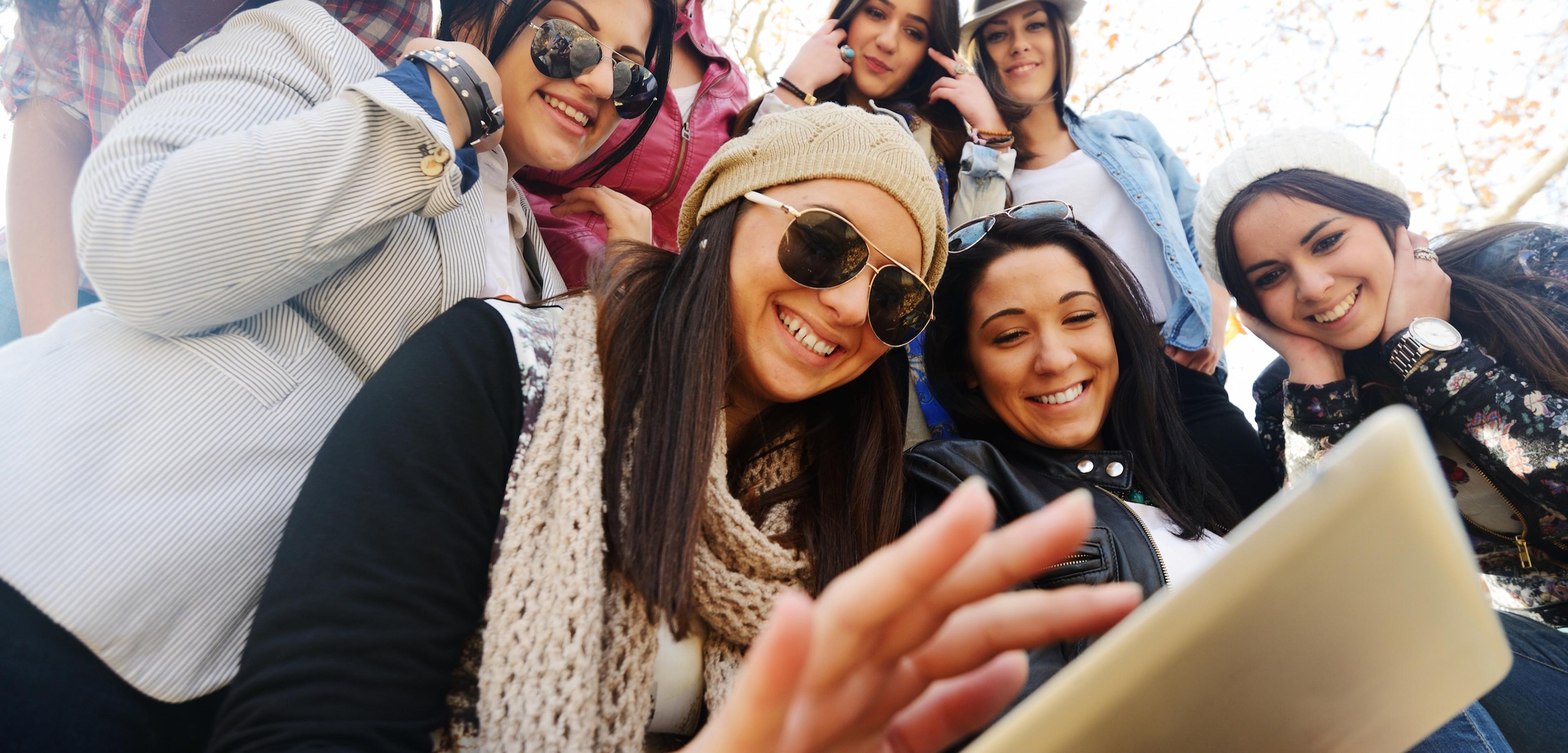 a group of young women are taking a selfie with a tablet representing active users