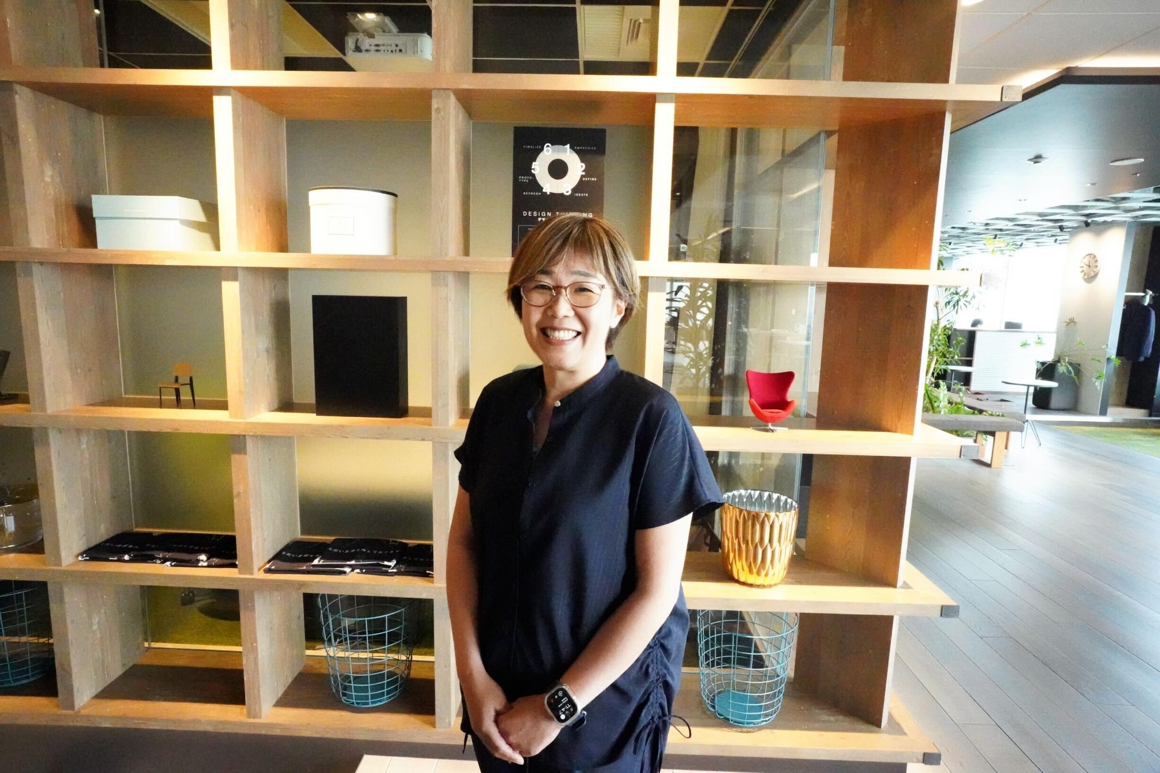 a woman is standing in front of a bookshelf and smiling .