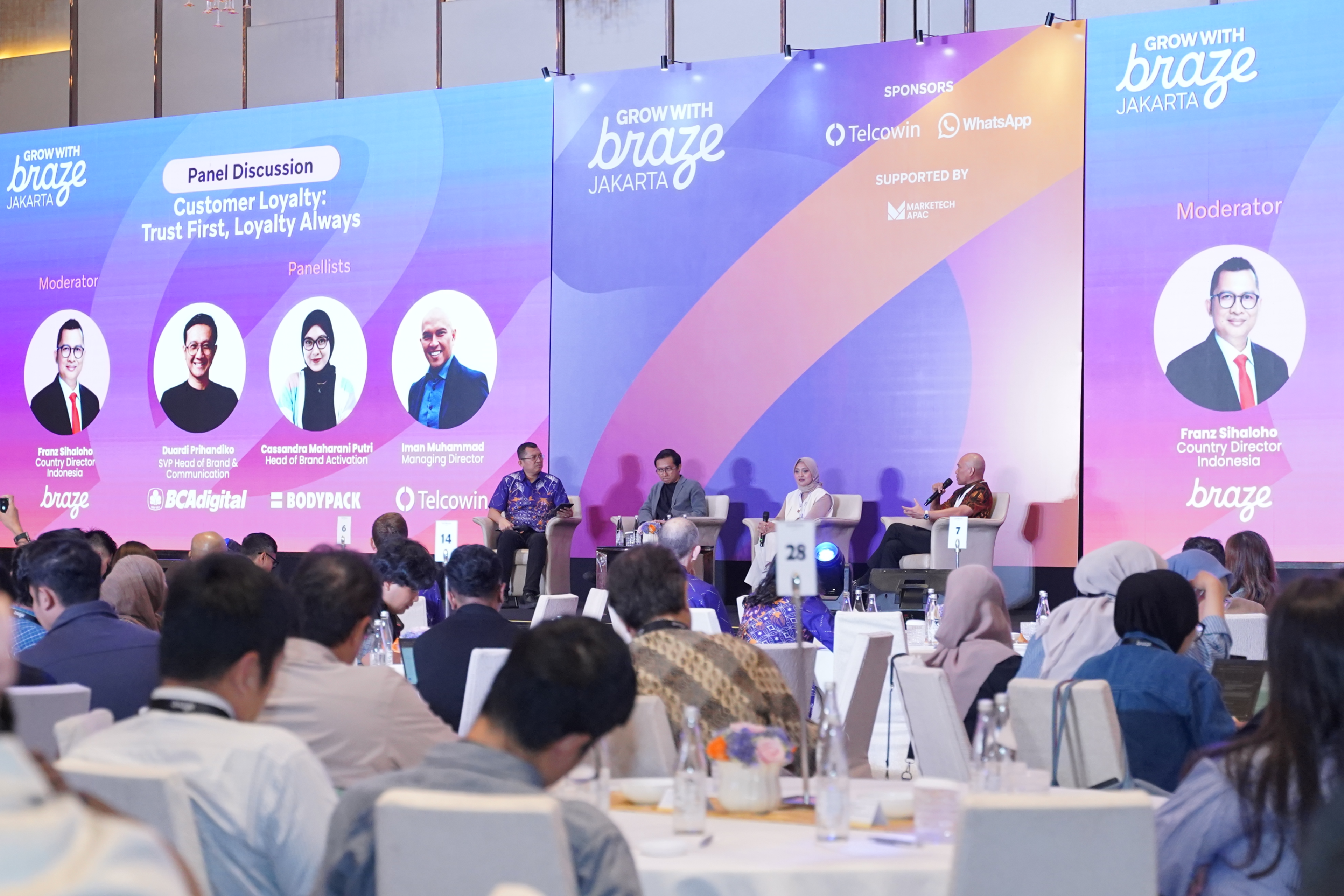 Panelists discuss customer loyalty onstage at the Grow With Braze Jakarta event as attendees watch from banquet tables.