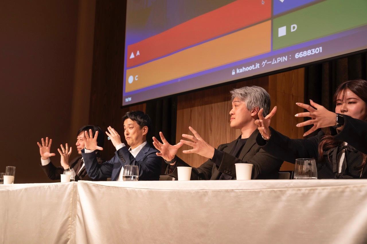 a group of people are sitting at a table with their hands in the air .