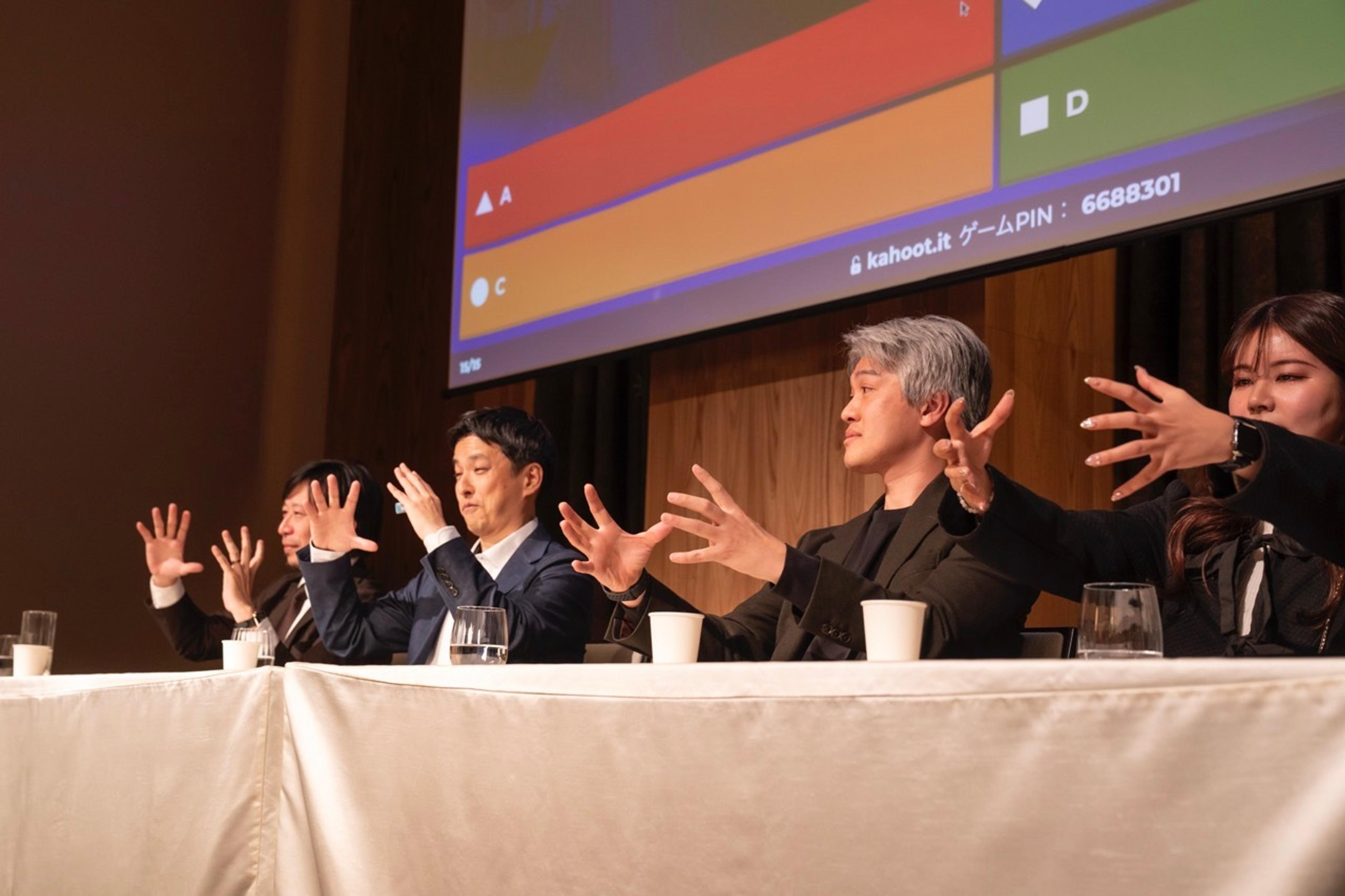 a group of people are sitting at a table with their hands in the air .