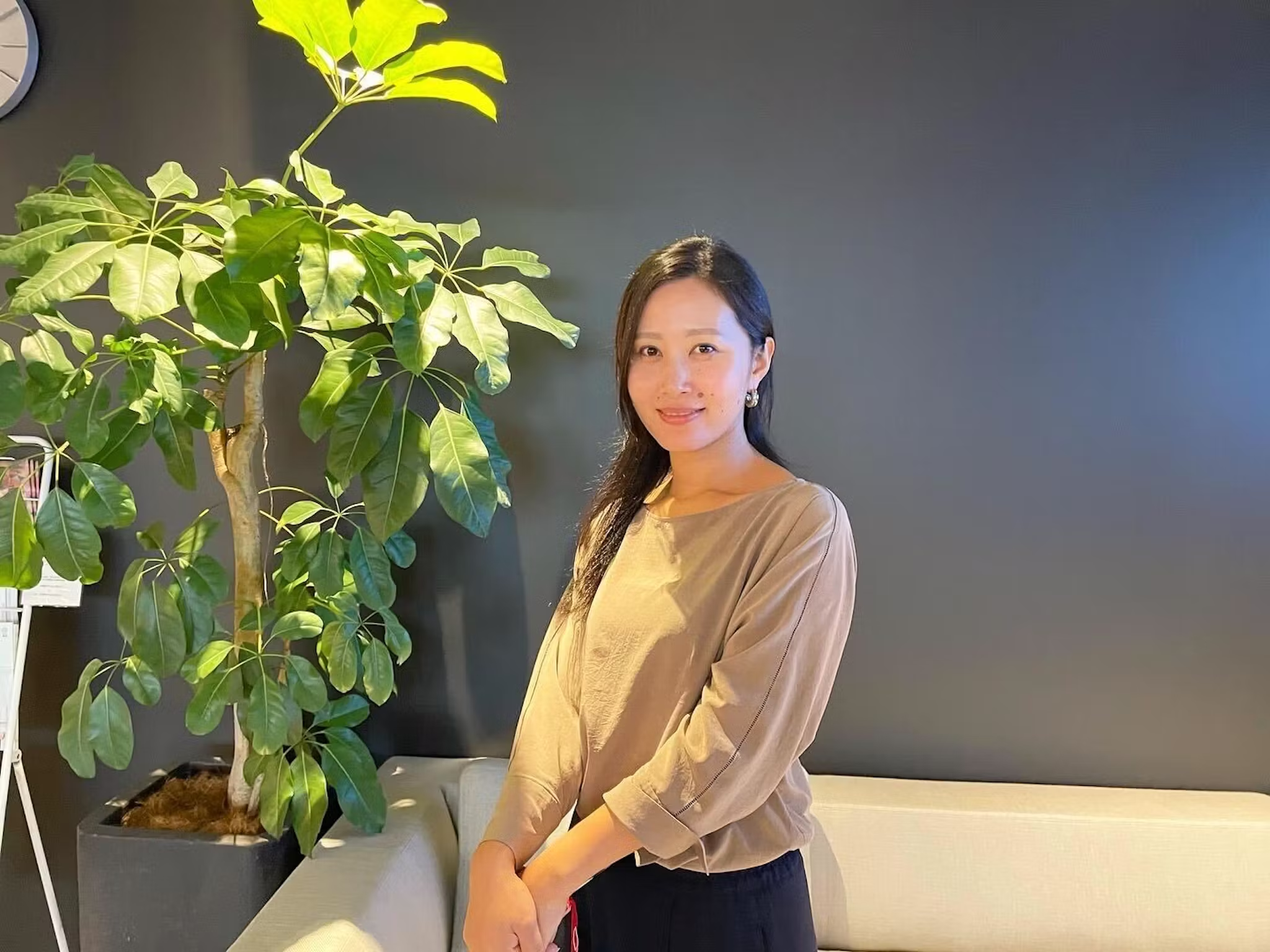 a woman stands in front of a potted plant