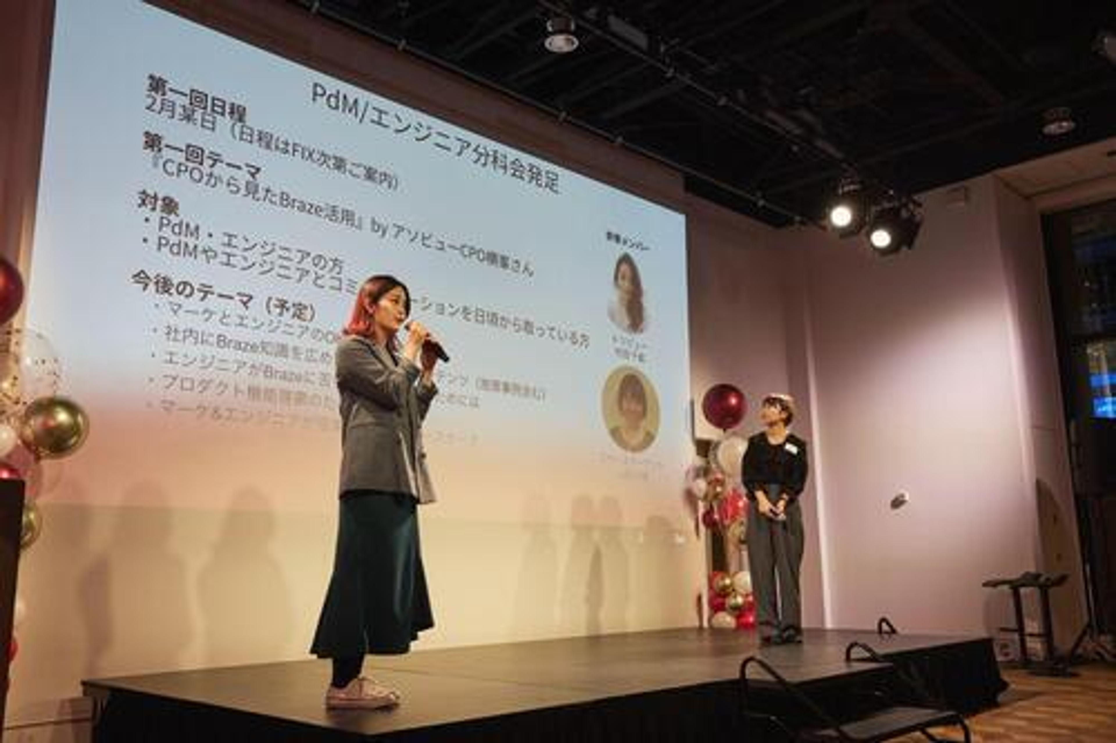 PdMエンジニアのイベントで、スピーカーがプレゼンテーションを行っています。背景にはスライドと装飾が見えます。