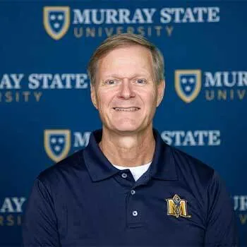 Smiling middle-aged man in a Murray State University polo shirt poses in front of a blue Murray State University backdrop.