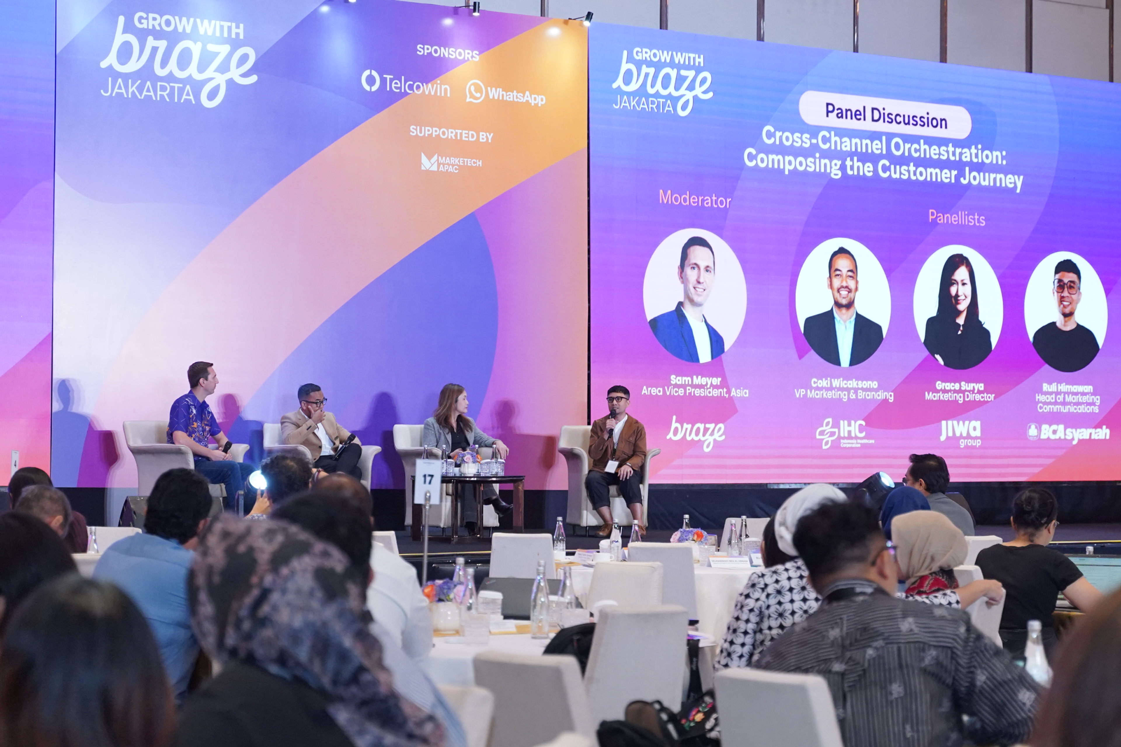 Four speakers participate in a panel discussion on cross-channel customer journeys at the Grow with Braze Jakarta conference, with attendees seated in the foreground.