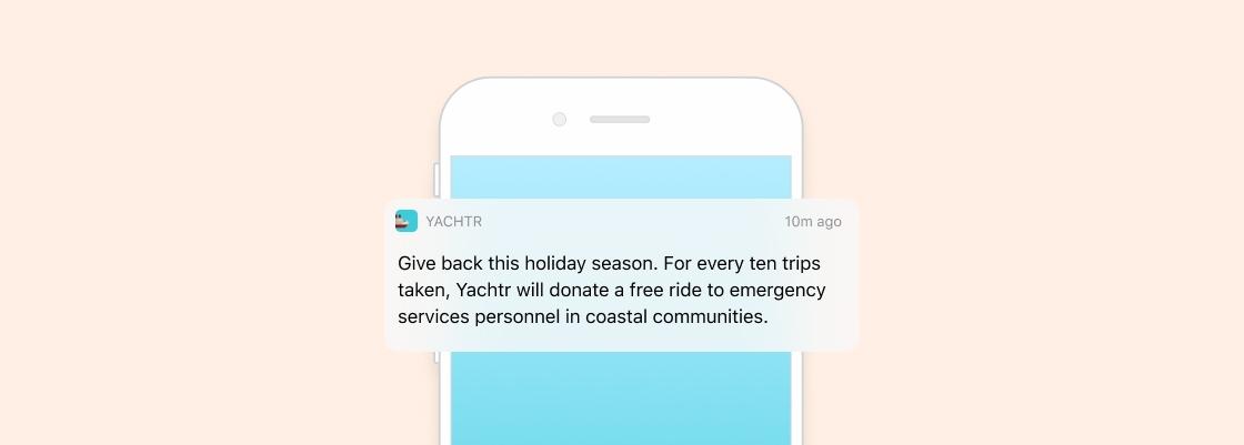 A smartphone notification from Yachtr announces a holiday season initiative to donate free rides to emergency services personnel for every ten trips taken. The background is a soft pastel color.