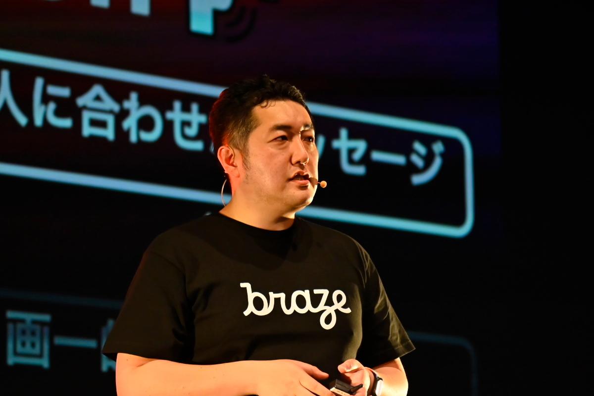 黒いTシャツを着た男性がステージで話しています。背景には「人に合わせたメッセージ」というテキストがあります。