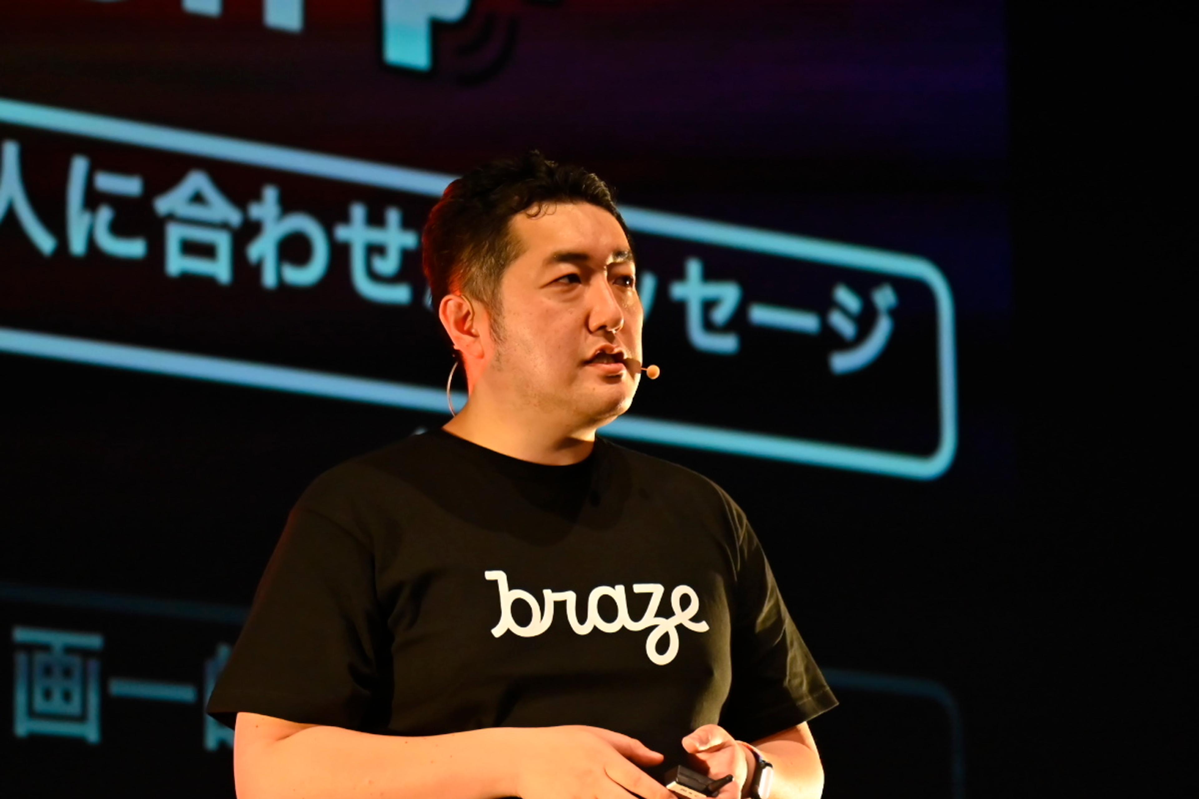 黒いTシャツを着た男性がステージで話しています。背景には「人に合わせたメッセージ」というテキストがあります。