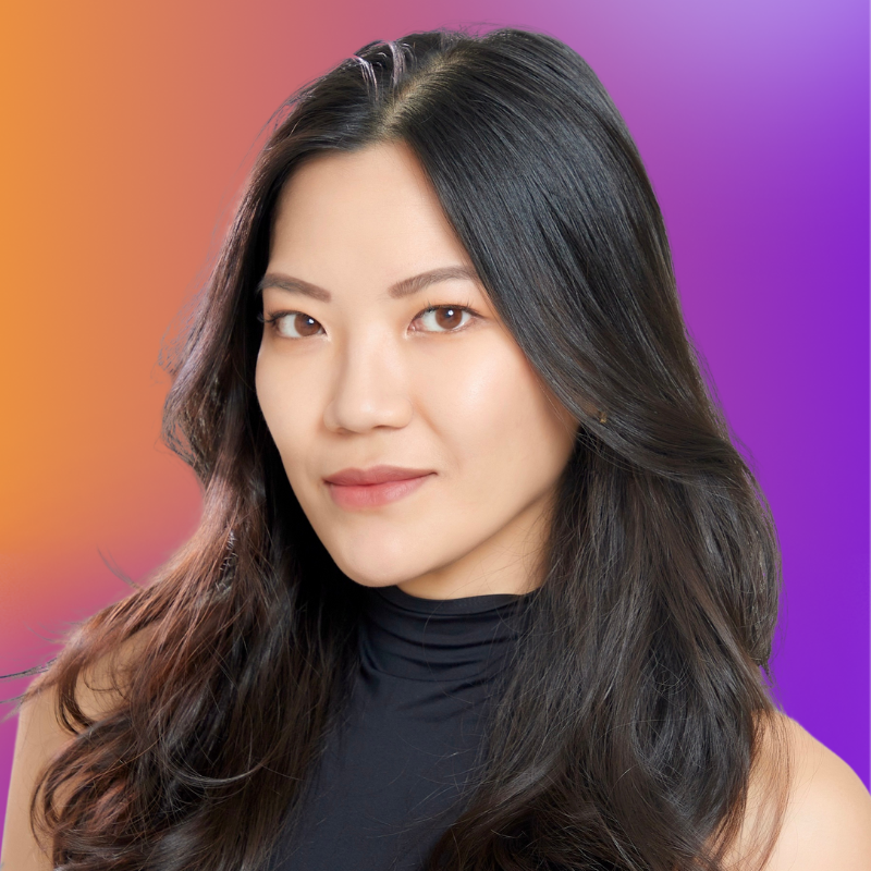 A woman with long, dark hair poses against a gradient background of orange and purple. She wears a black sleeveless top and has a confident expression.