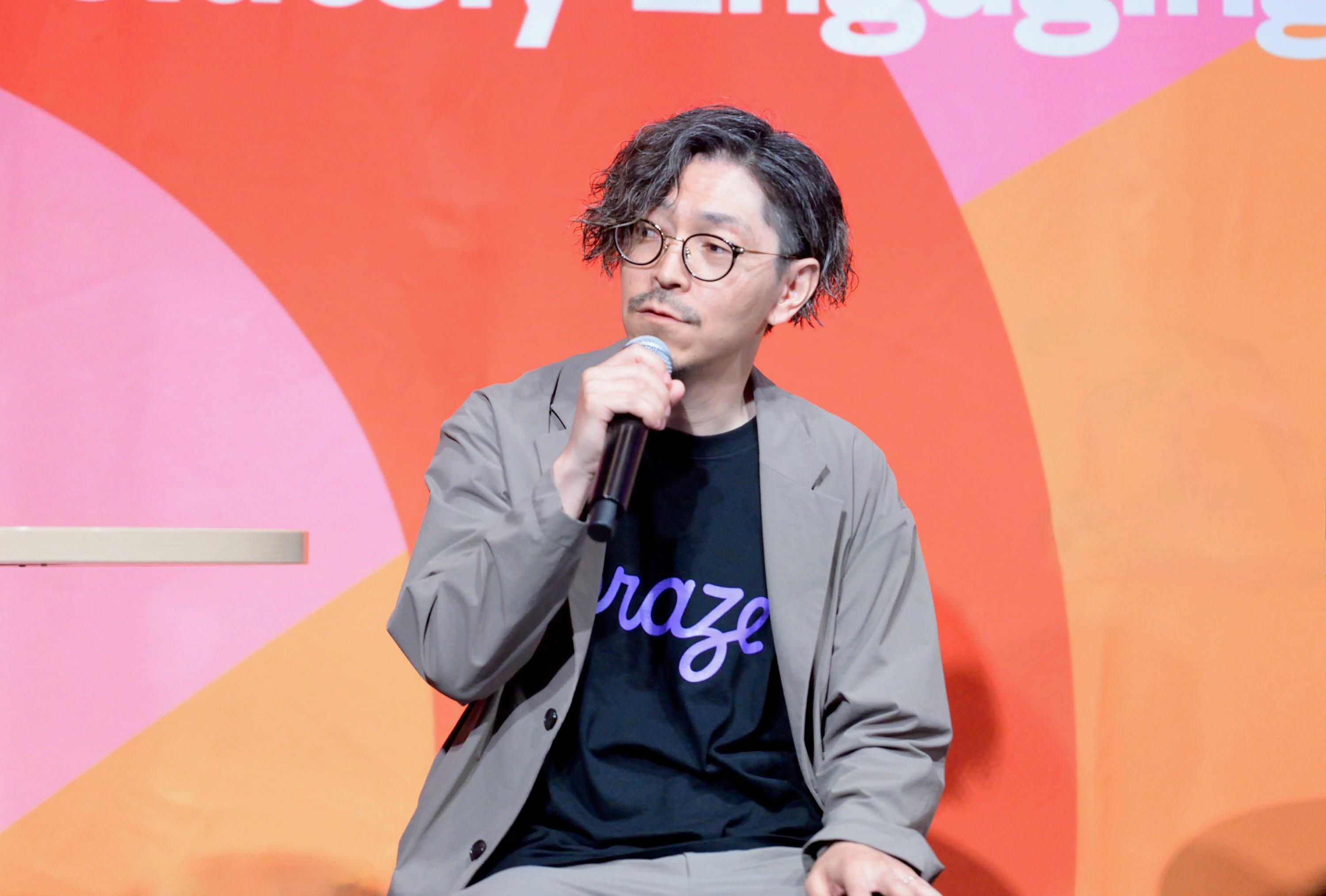 a man in a suit and glasses is sitting in front of a microphone .