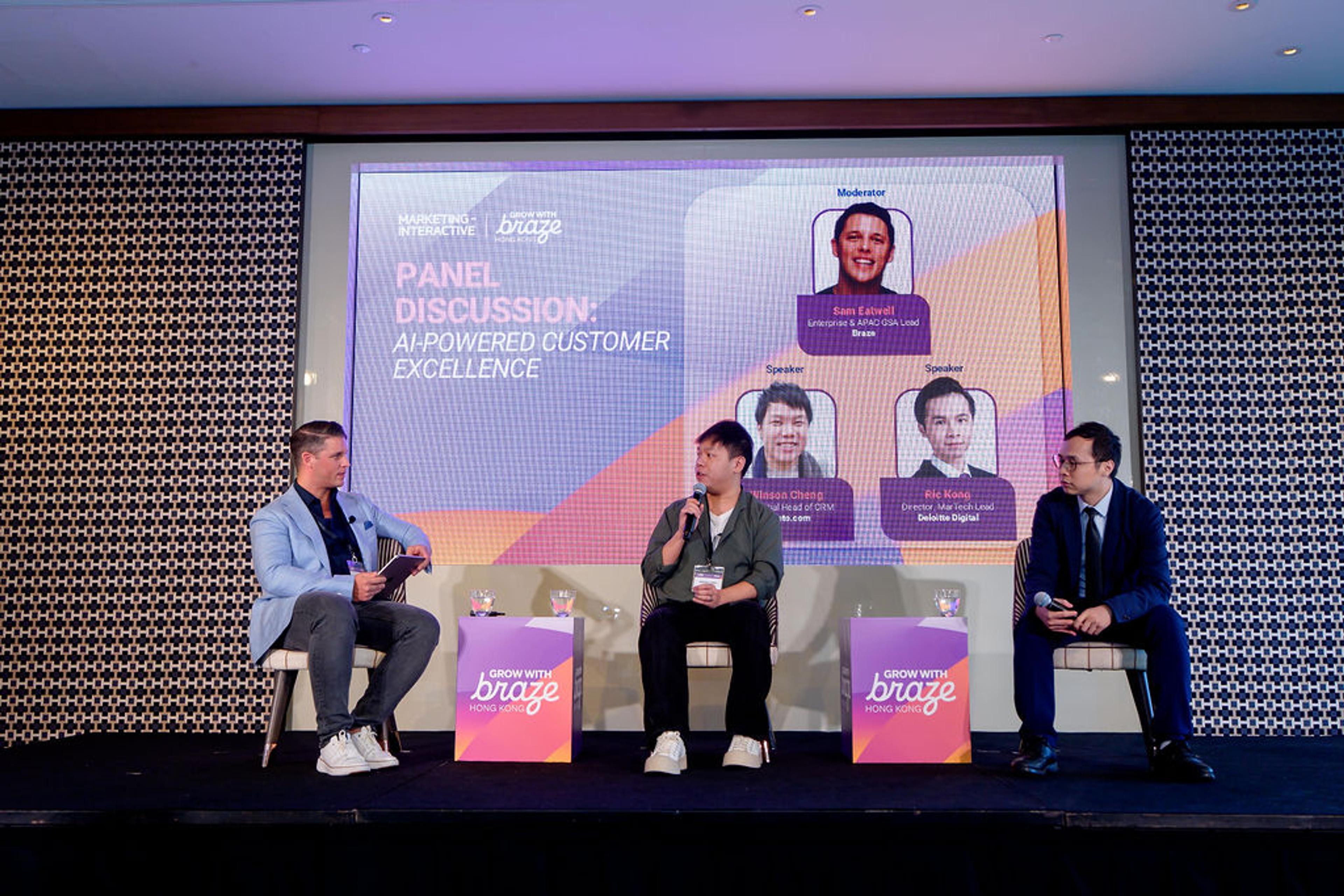 Panel discussion on AI-powered customer excellence with three speakers on stage in front of a large screen.