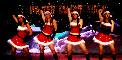 Four dancers in festive Santa costumes perform on stage, with a winter-themed backdrop and "Winter Talent Show" displayed above them.