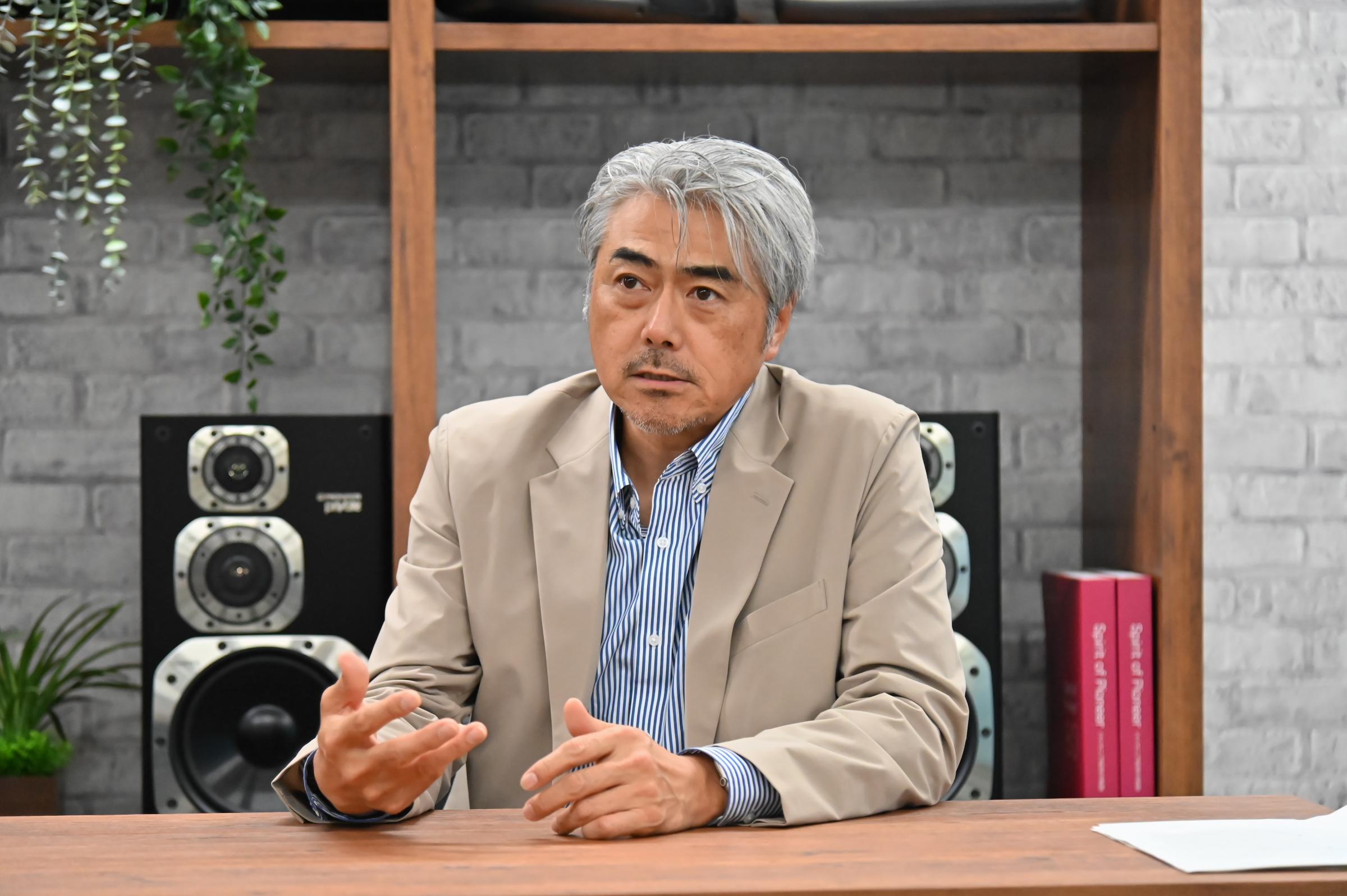 a man in a suit is sitting at a table talking to someone .