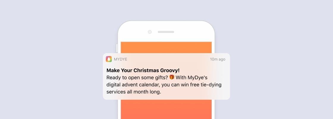 A smartphone notification from MyDye promoting a digital advent calendar with a chance to win free tie-dying services. The background is light purple with an orange accent.