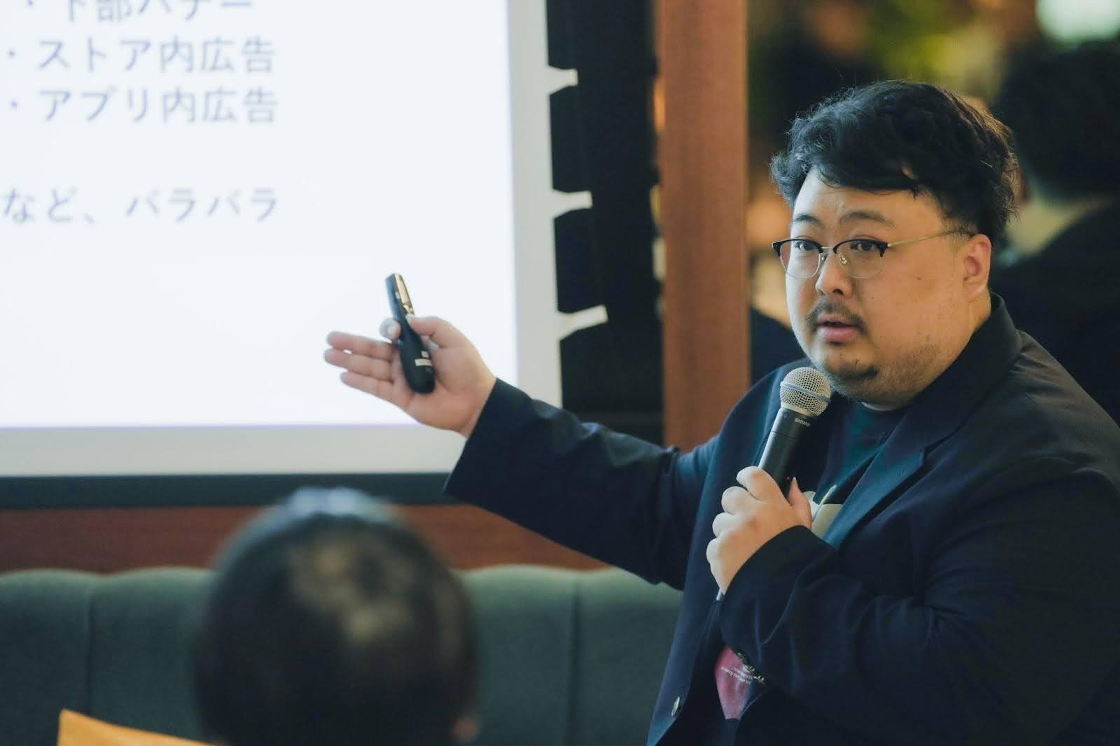 a man is holding a microphone and giving a presentation to a group of people .