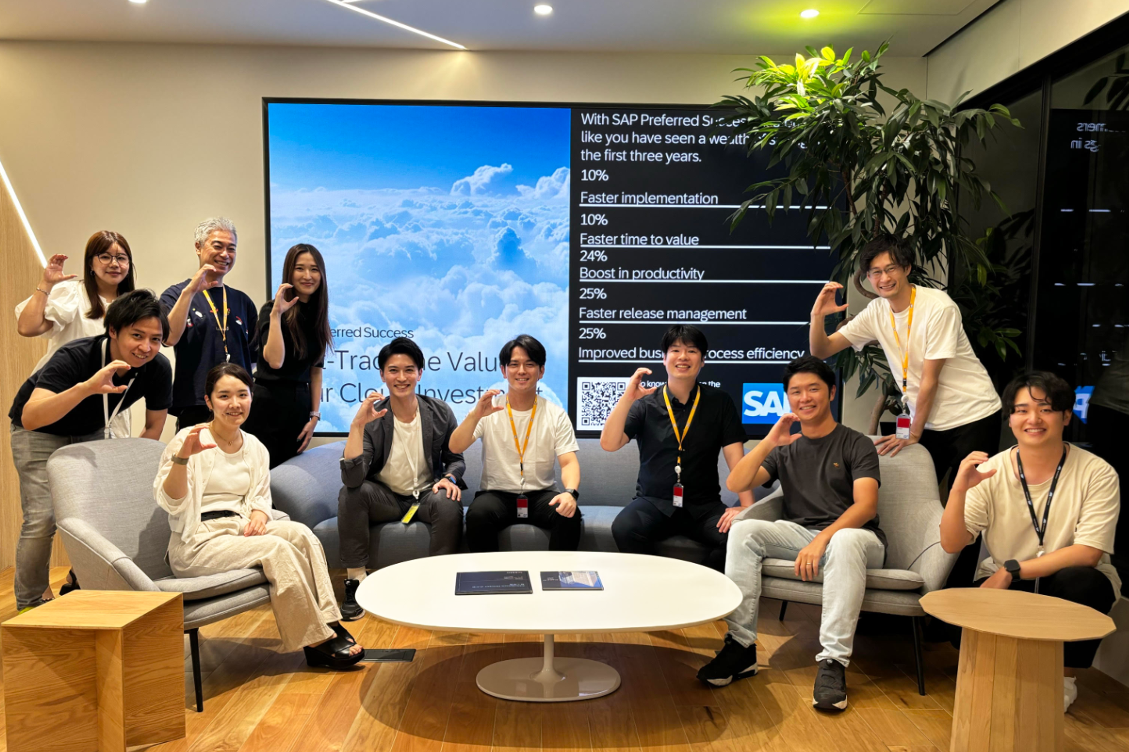 SAPのオフィスで、チームメンバーが集まってポーズをとっています。背景には「SAP Preferred Success」のメッセージが表示されています。