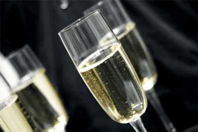 Four champagne flutes filled with sparkling champagne against a dark background. Bubbles rise in the glasses.