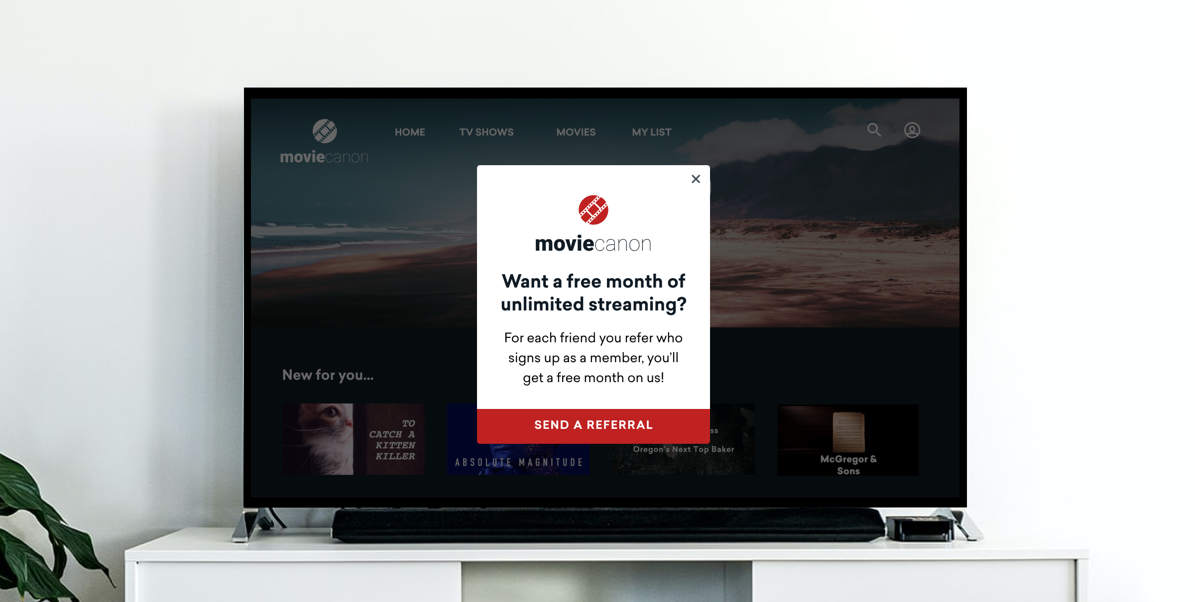 A television screen displaying a streaming service interface with a pop-up message offering a free month of unlimited streaming for referrals. The background shows a scenic image.