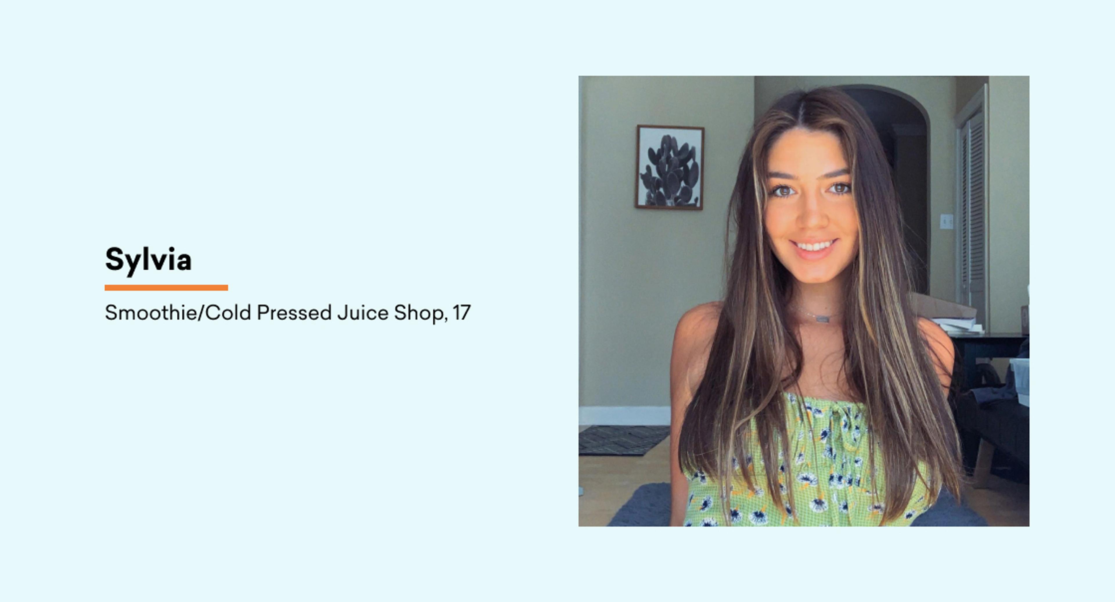 A young woman with long, straight hair smiles at the camera, wearing a green patterned top. The background features a light-colored wall and a plant.