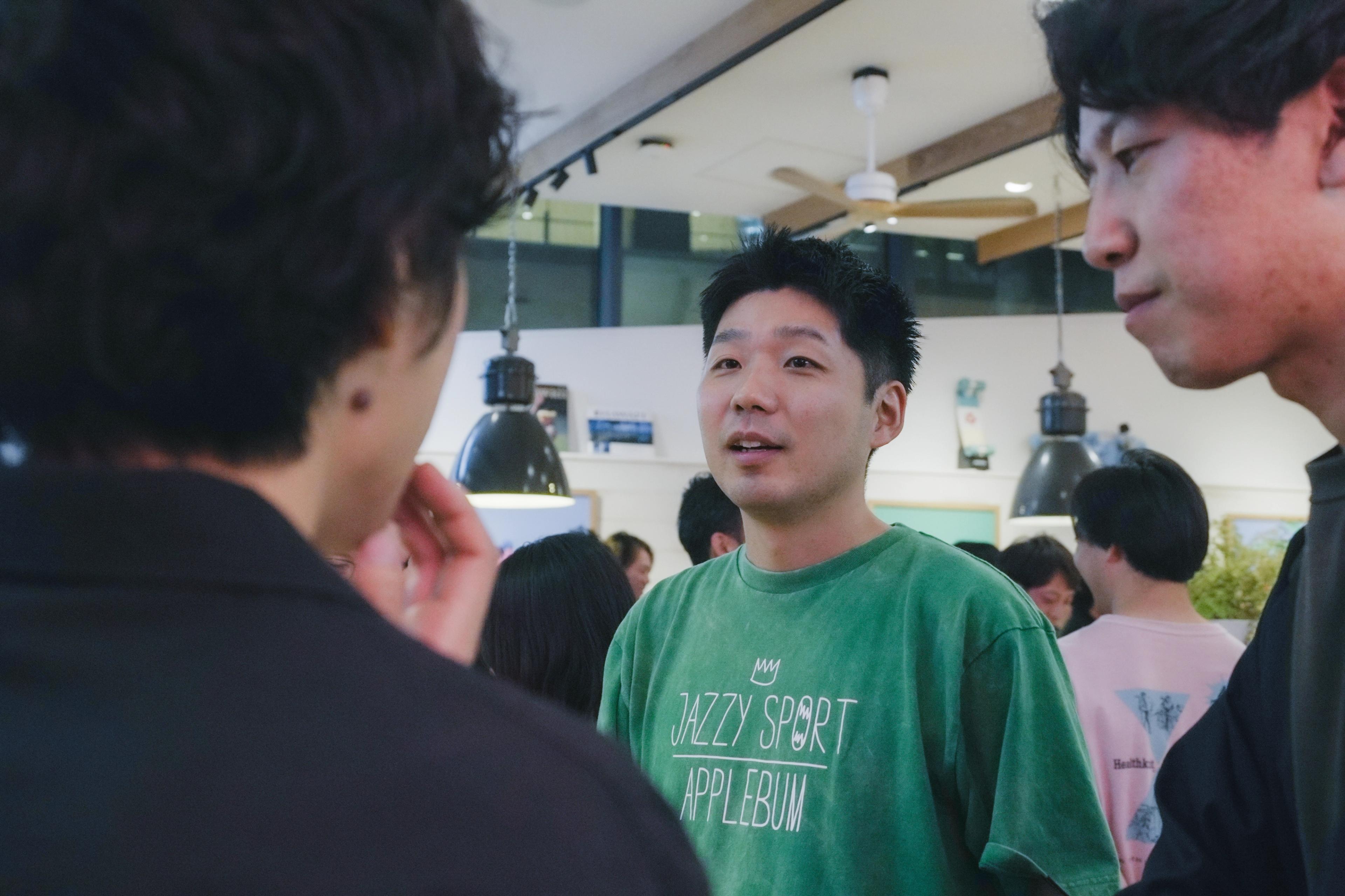 a group of young men are standing in a room talking to each other .