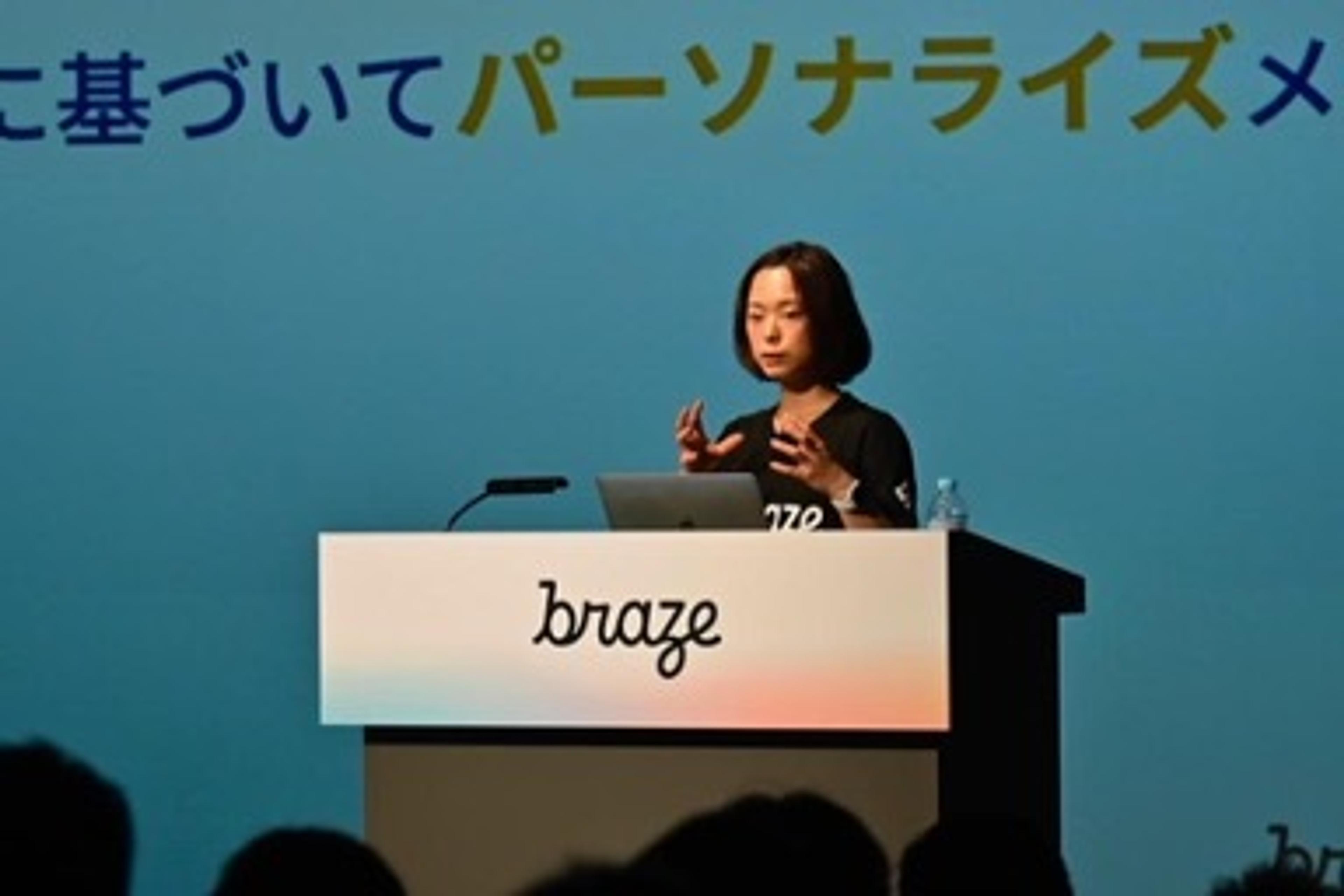 プレゼンテーションを行う女性が、スライドの前で手を使って説明しています。背景には「パーソナライズメッセージ」と書かれています。