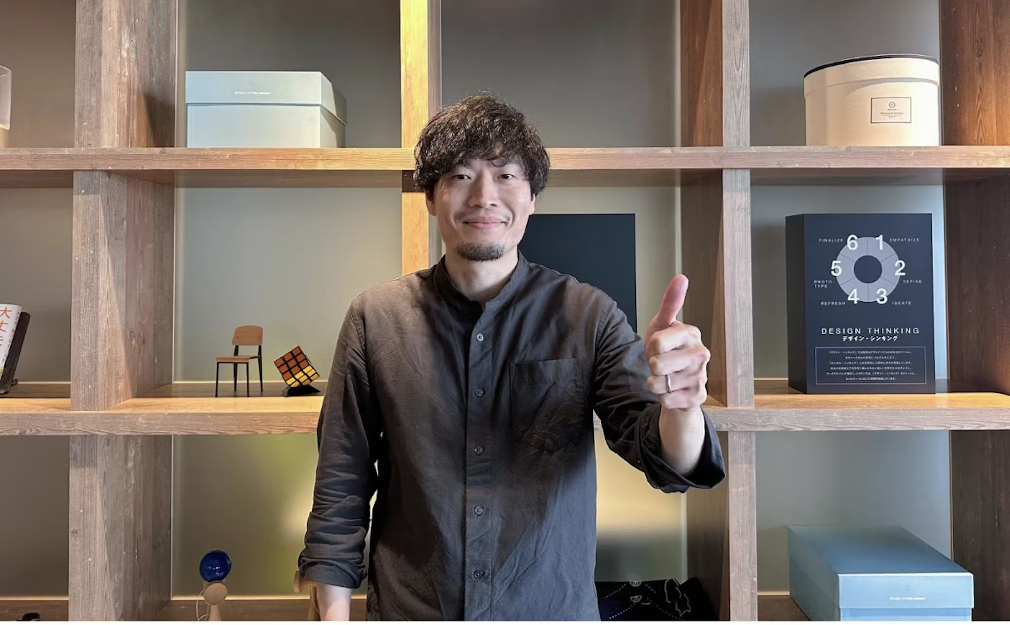 a man giving a thumbs up in front of a book titled design thinking