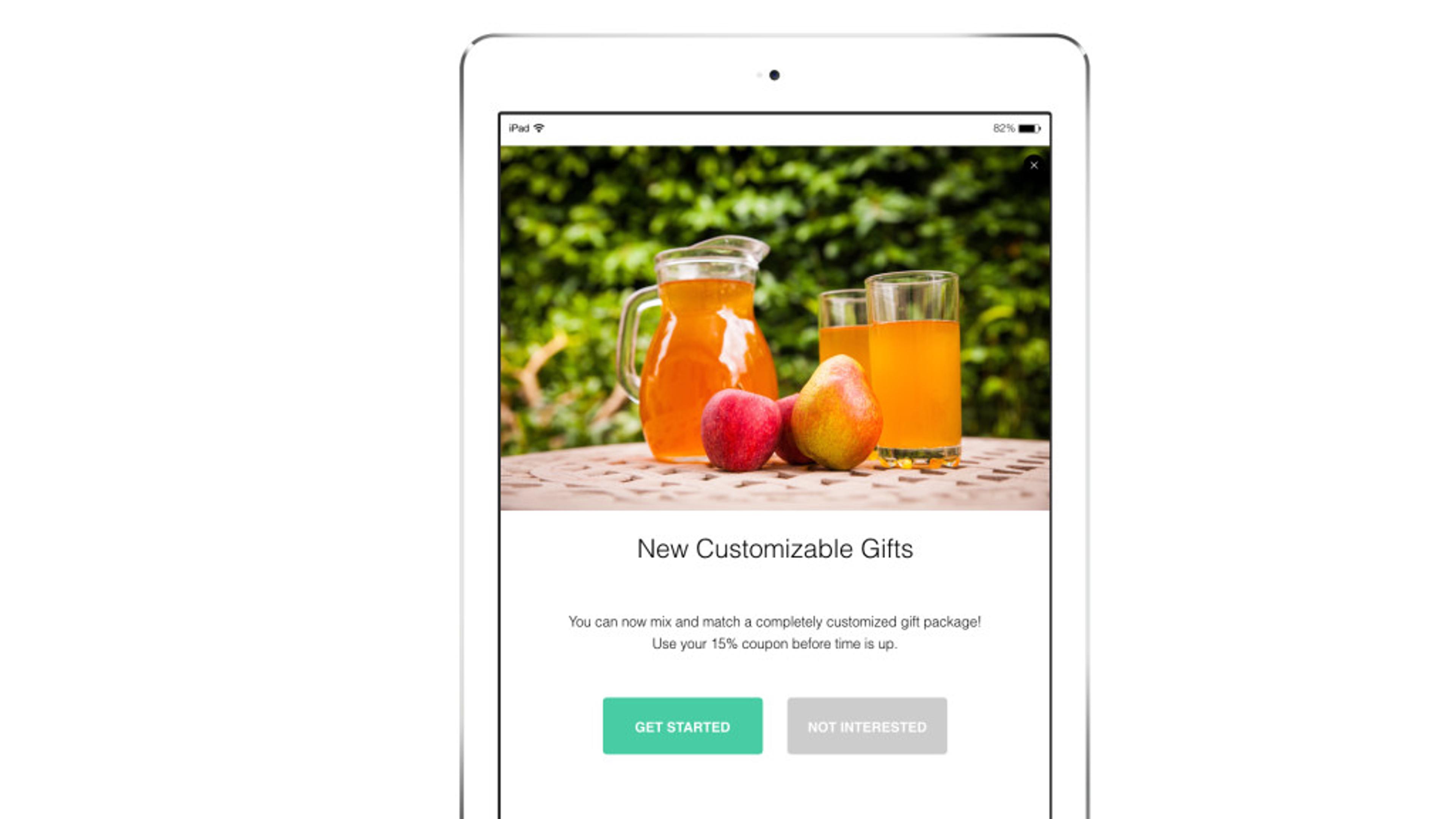 A tablet displaying a promotional message for customizable gifts, featuring a pitcher of orange drink and two apples on a table.