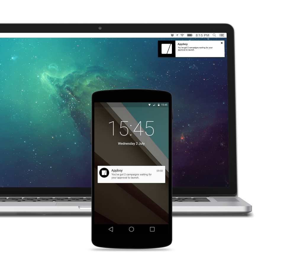 A smartphone displaying a notification with the time and date, positioned in front of a laptop showing a colorful galaxy background.