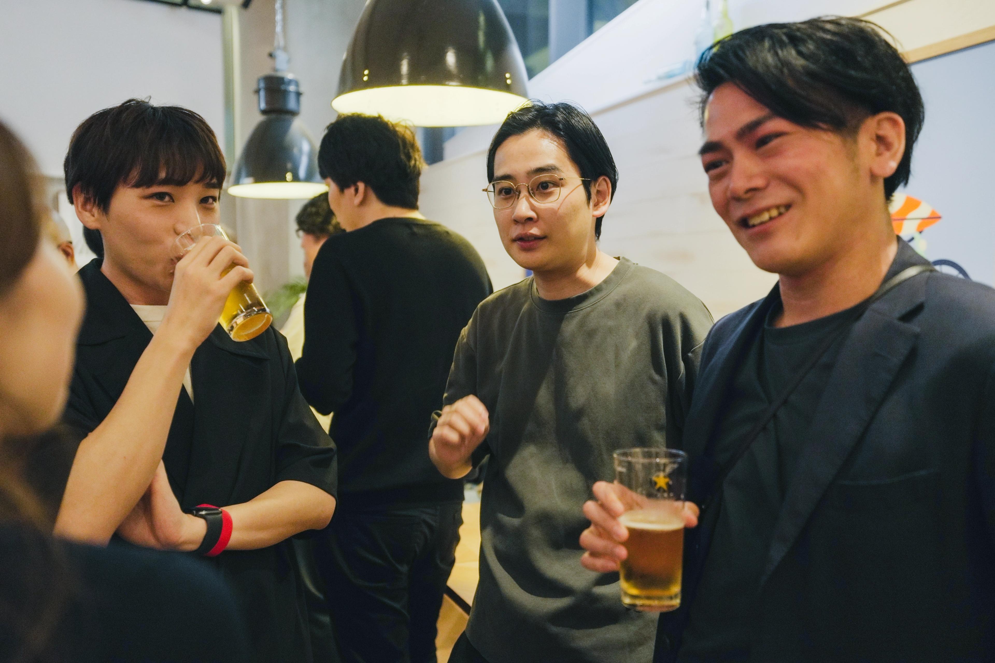 a group of people are standing around a table drinking beer .