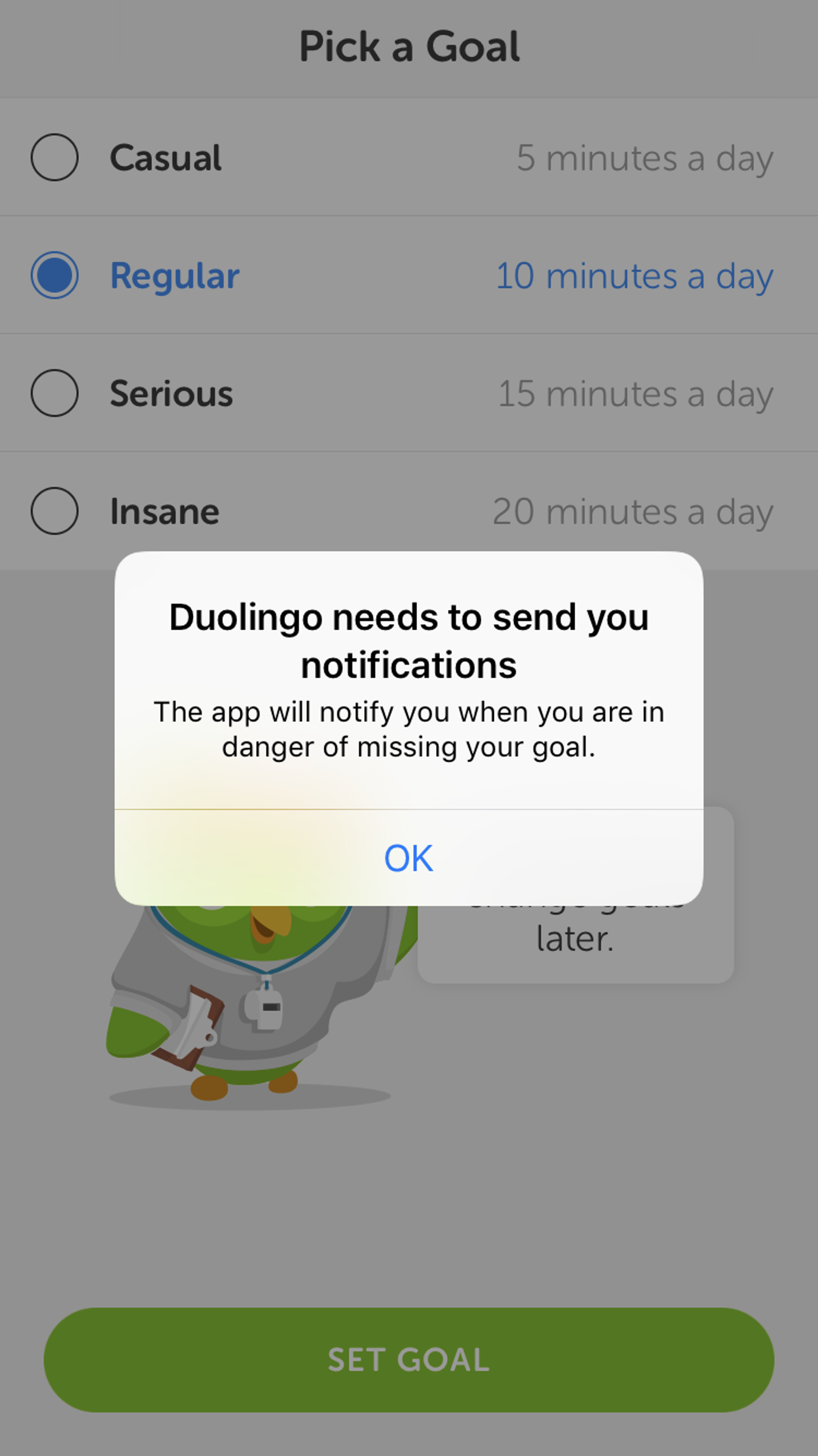 A pop-up message from the Duolingo app prompts the user to set a daily language learning goal, with options ranging from casual to insane. A cartoon owl character is shown at the bottom, encouraging the user to engage.