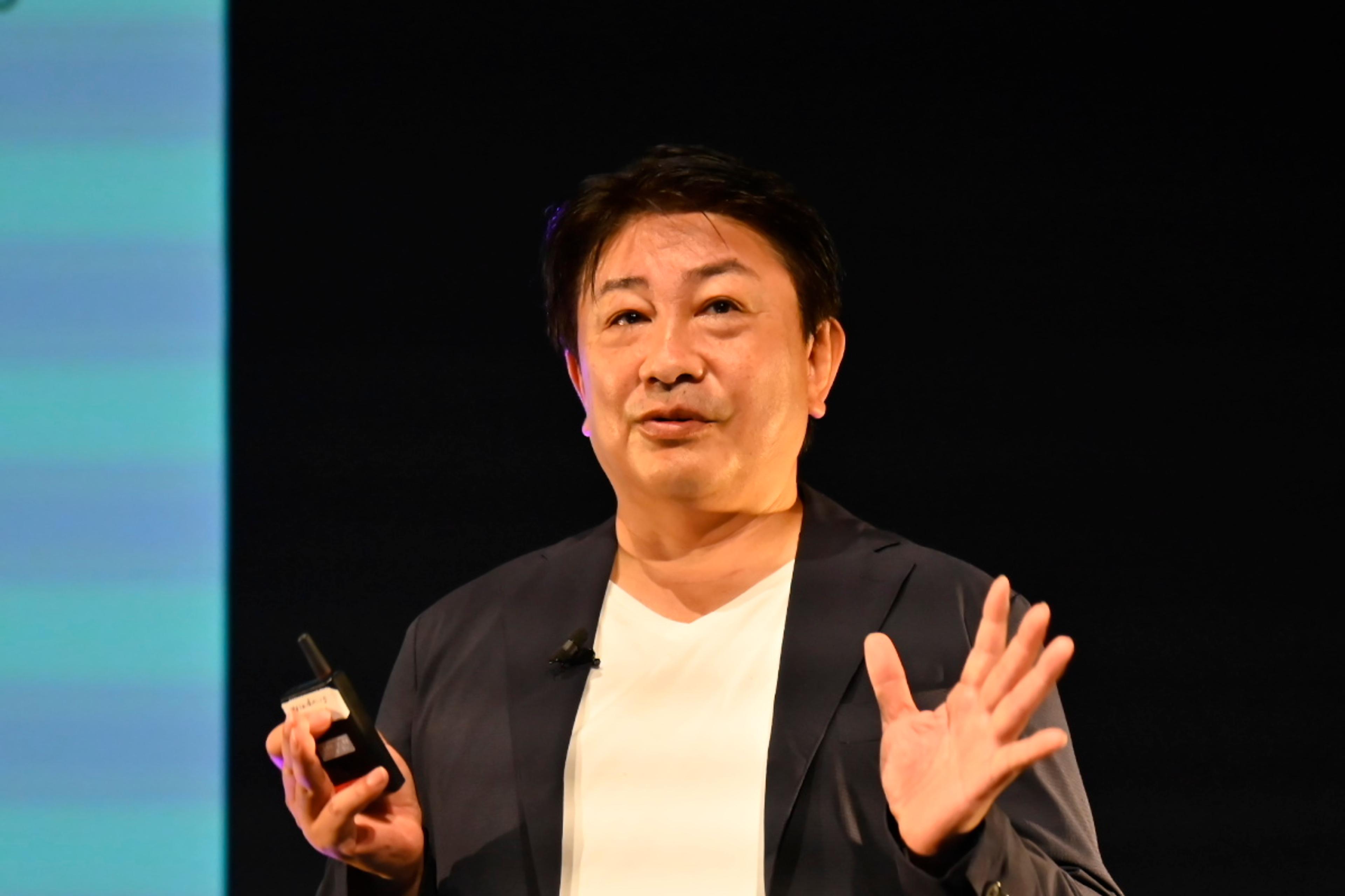 男性がプレゼンテーションを行っている様子。手を挙げて話している。