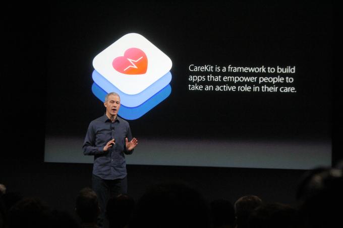 A speaker presents information about CareKit, a framework for building apps that help individuals take an active role in their healthcare. The background features a graphic related to the CareKit logo.