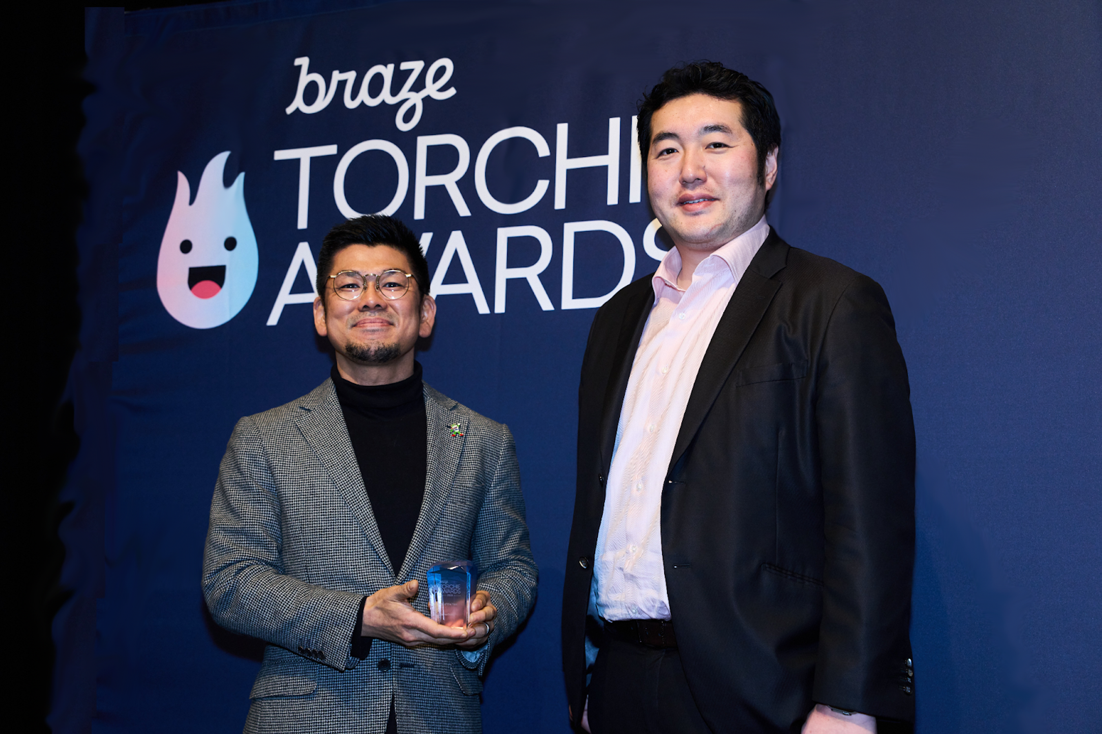 受賞者がトロフィーを持って立っている写真。背景には「BRAZE TORCH AWARDS」のロゴが見える。