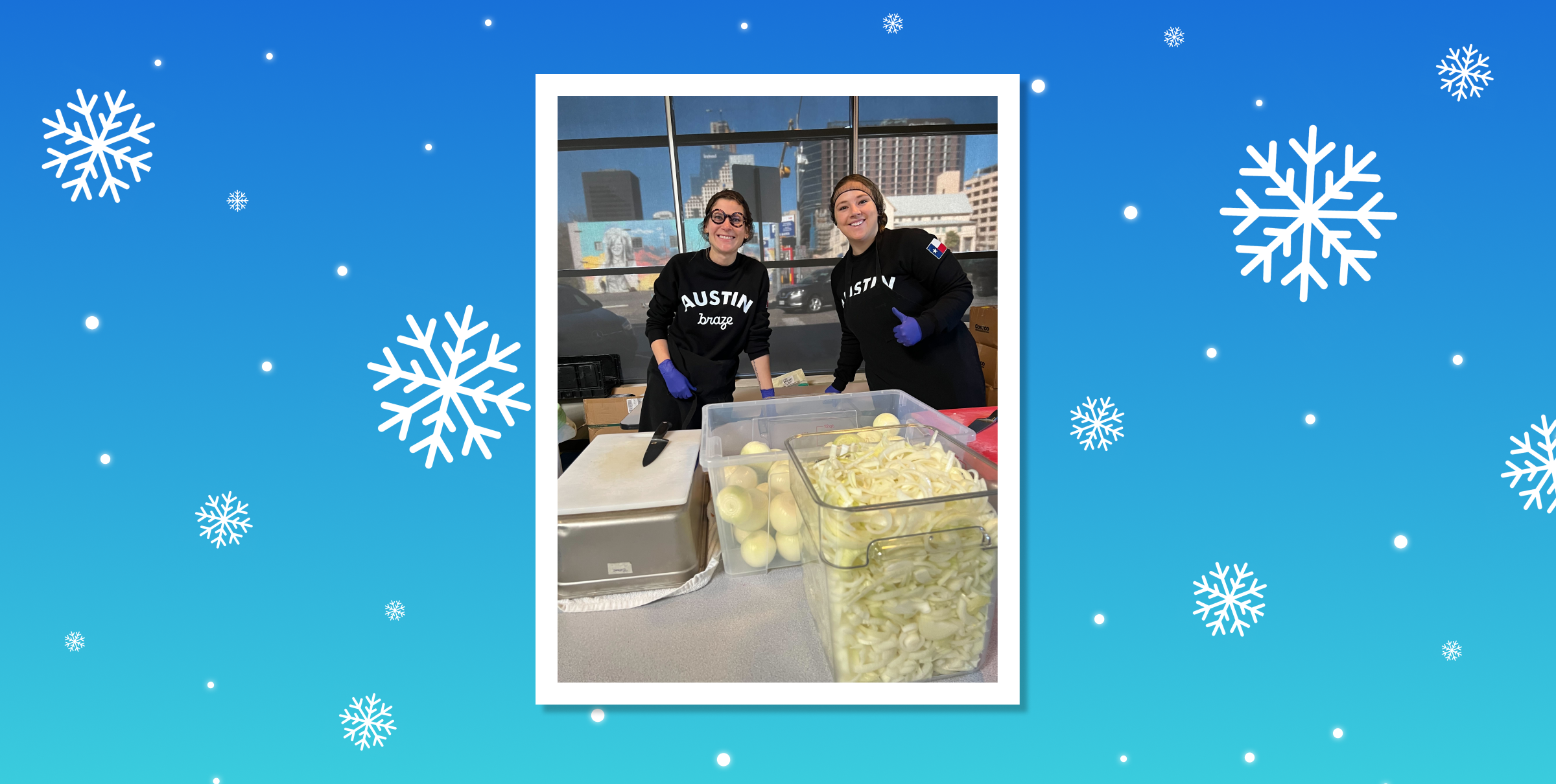 Two volunteers wearing matching black shirts smile while preparing food in a kitchen setting, with containers of sliced apples and other ingredients in front of them. The background features a winter-themed design with snowflakes.