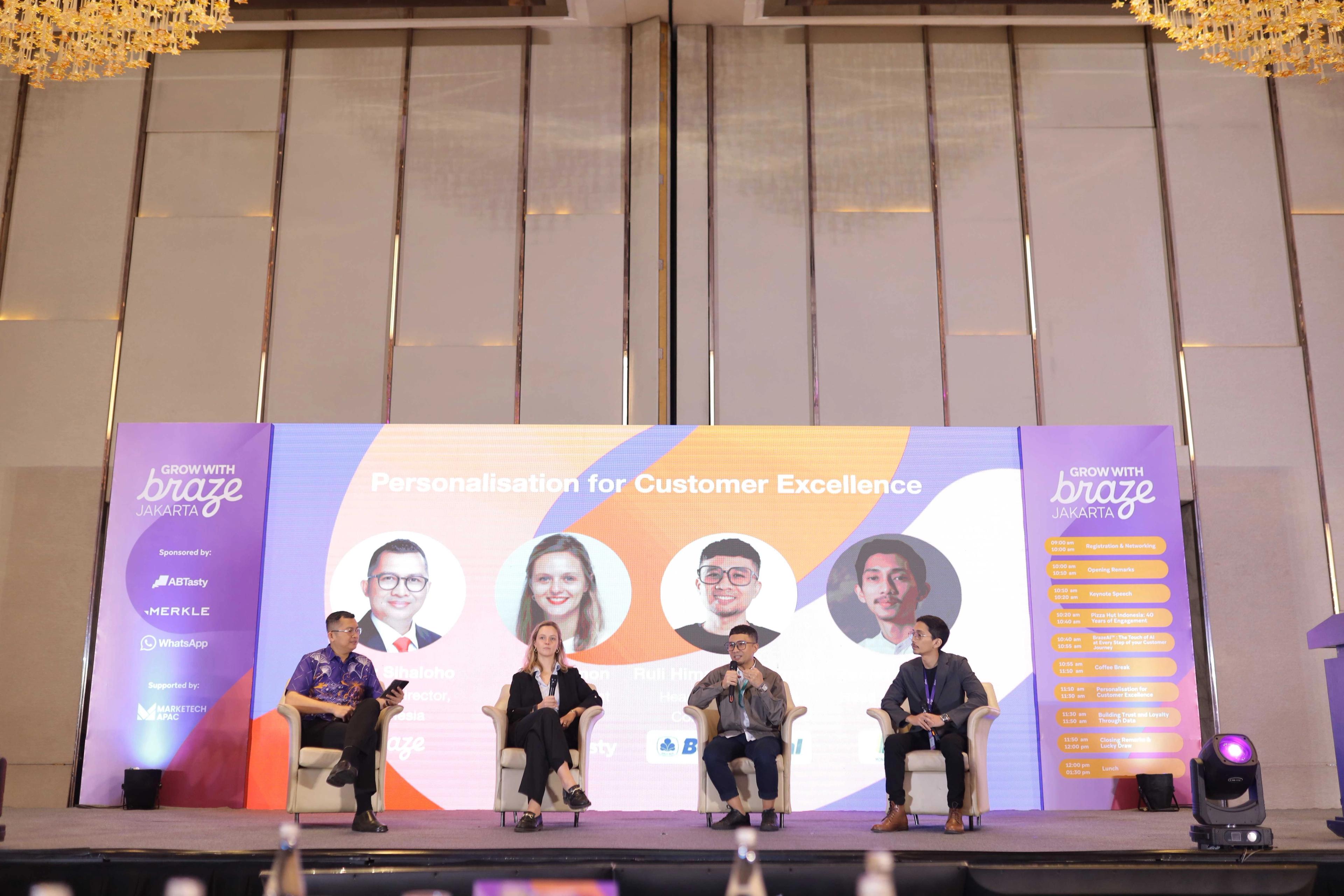 a group of people are sitting on a stage in front of a large screen .