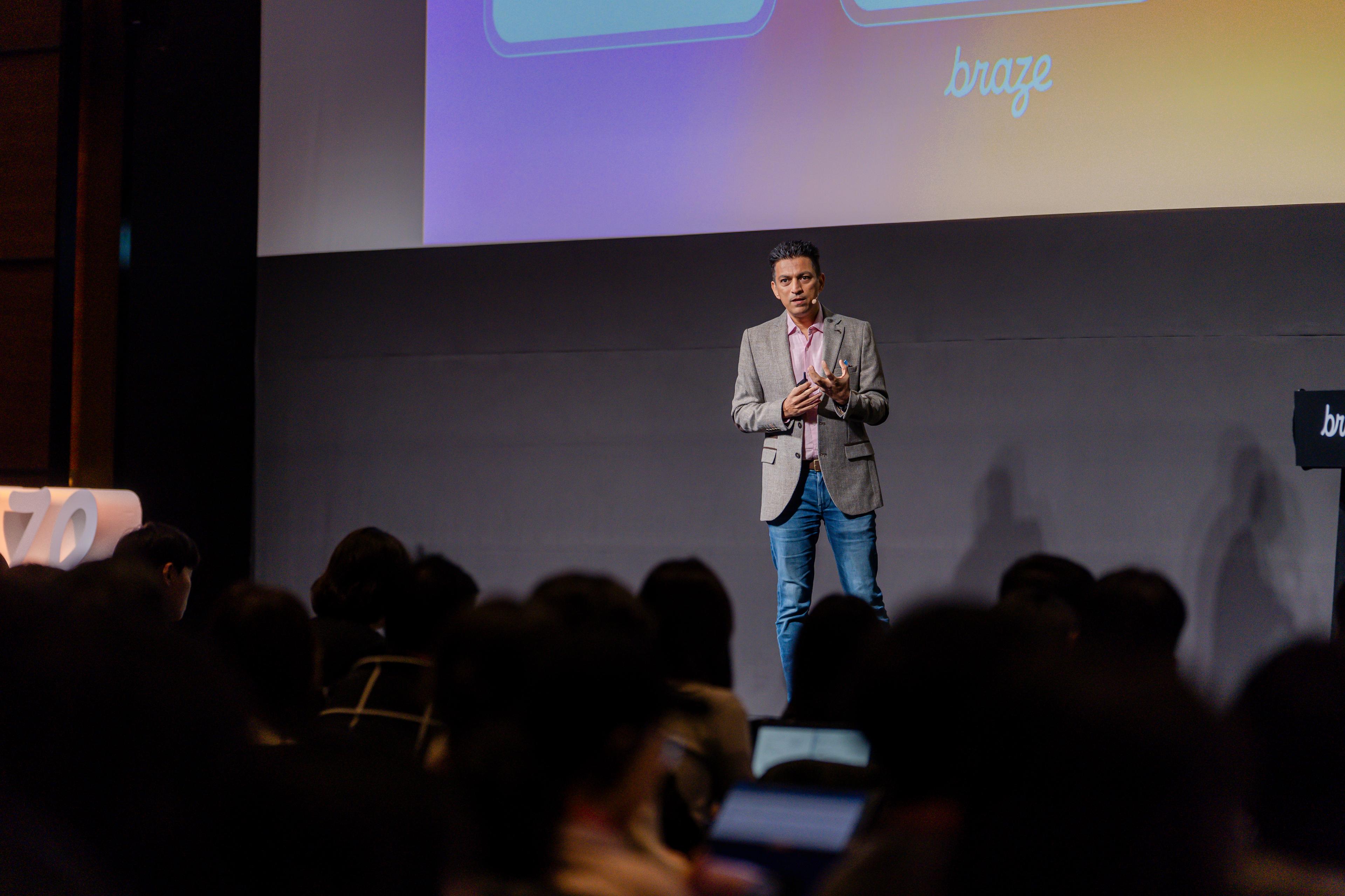 a man is standing on a stage giving a presentation to a crowd of people .