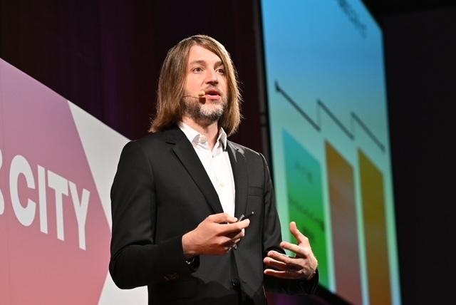 男性がプレゼンテーションを行っている。背景にはグラフが表示されている。