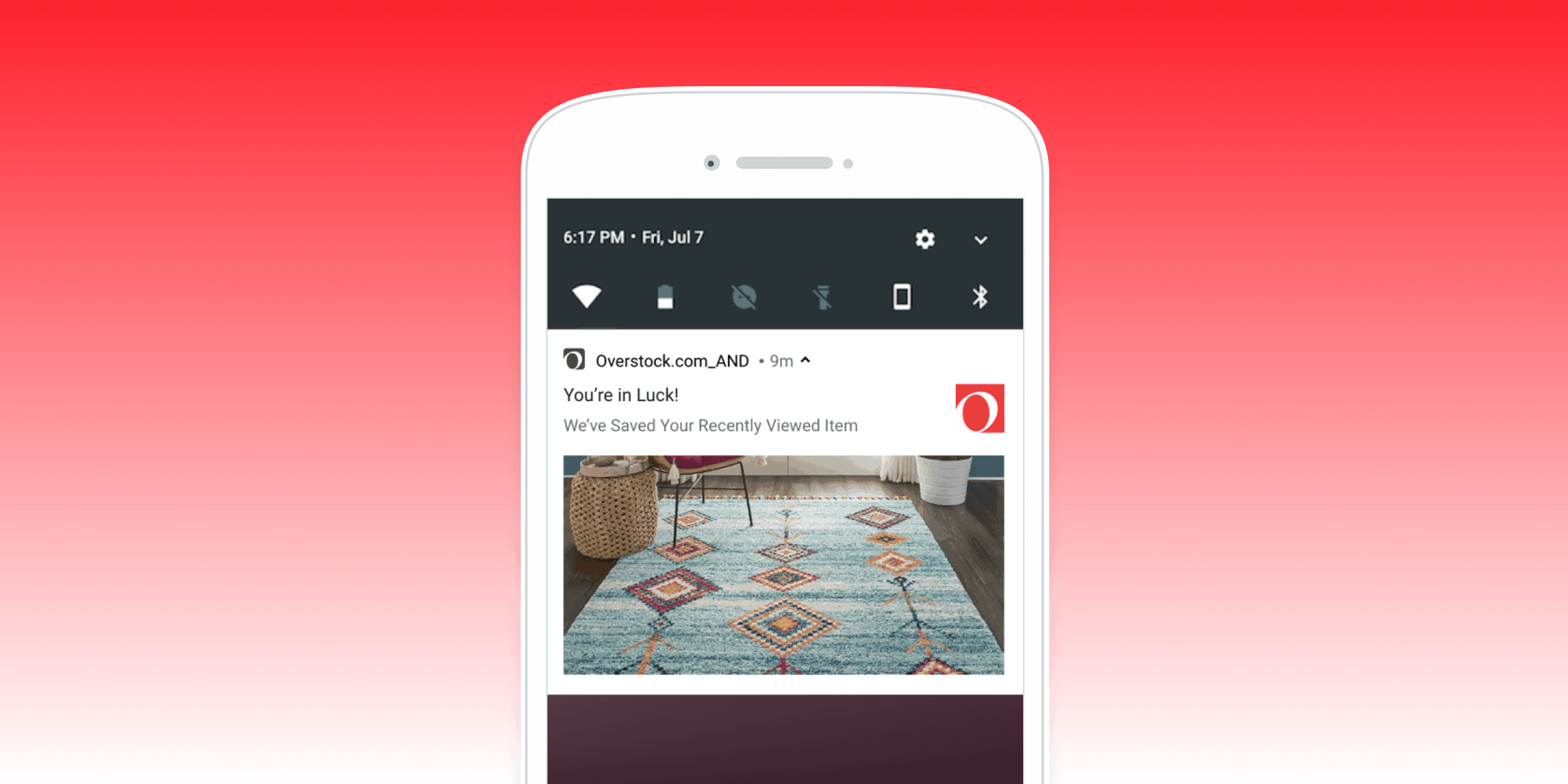 A smartphone screen displaying a notification from Overstock.com about a recently viewed item, featuring a colorful area rug. The background is a gradient from red to pink.