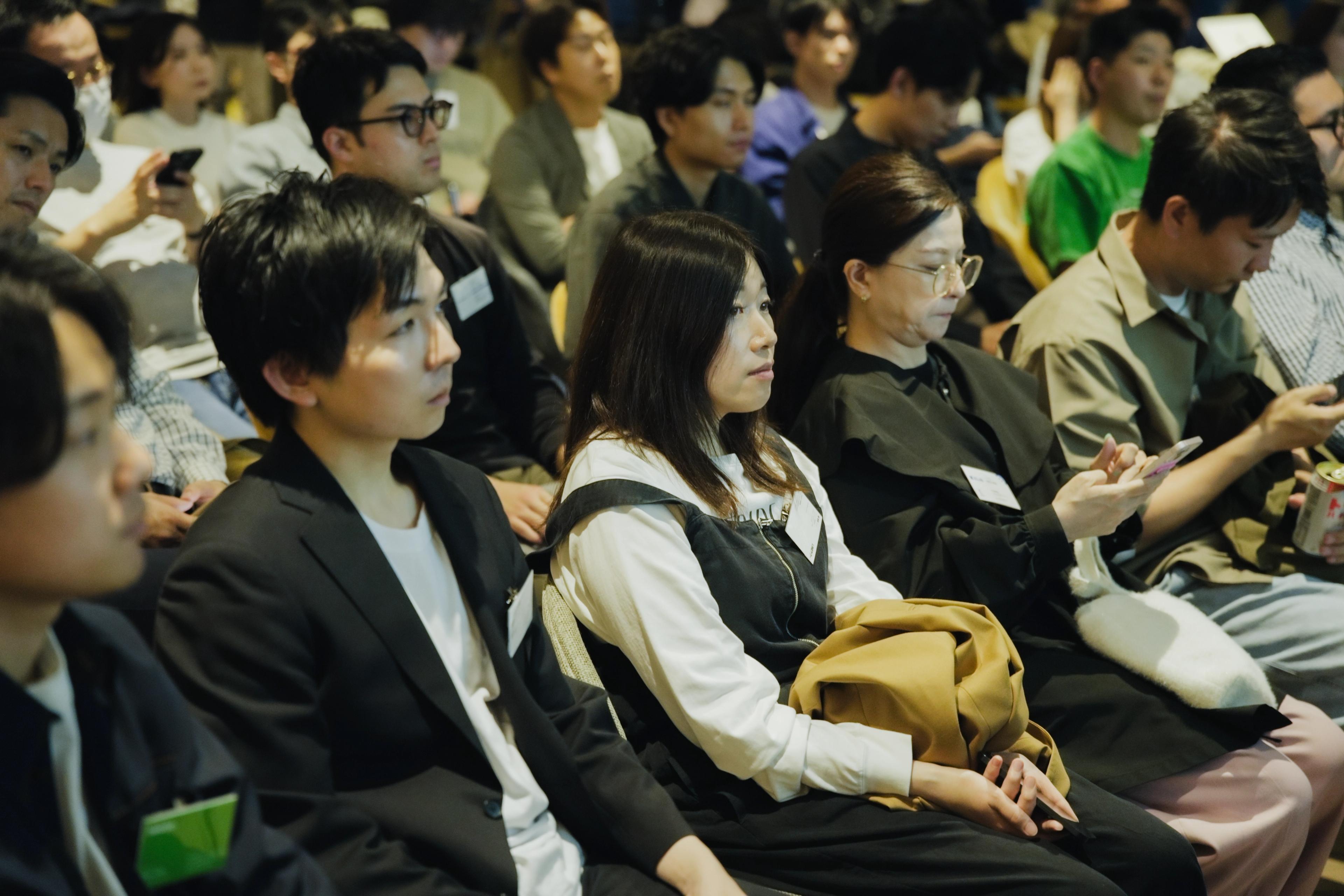 a group of people are sitting in a room watching a presentation .