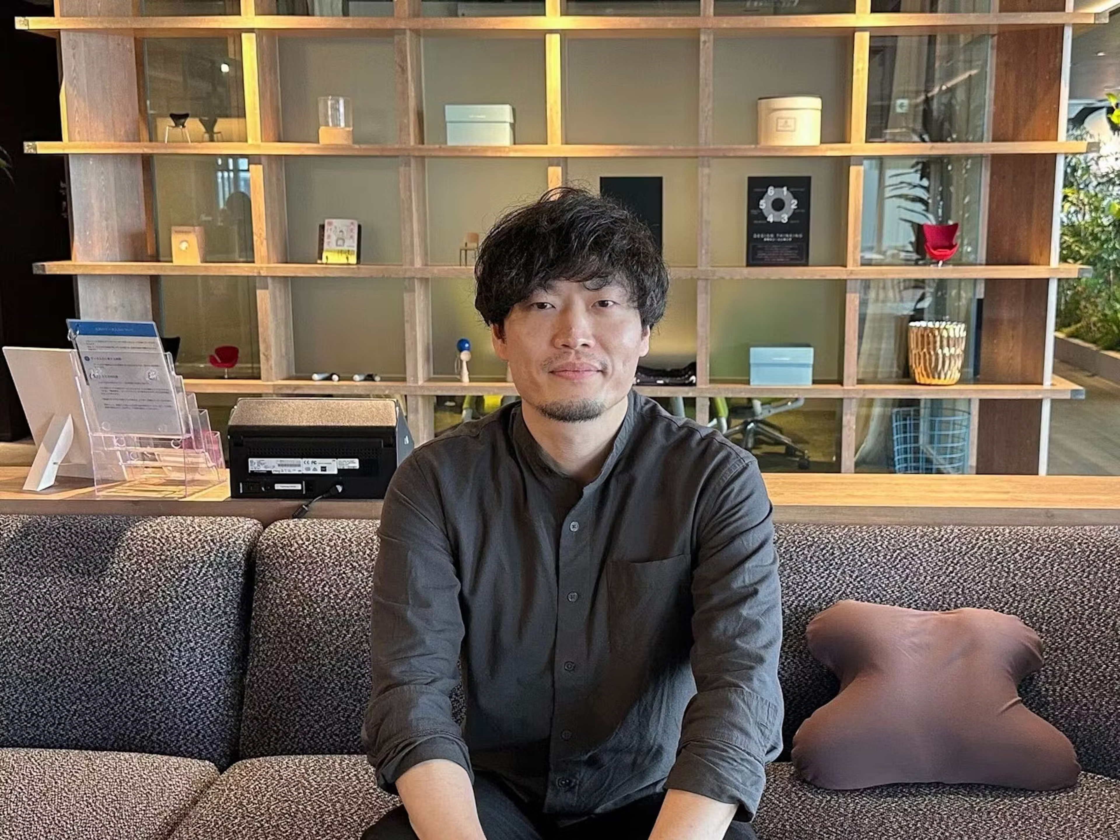 a man sits on a couch in front of a shelf with a sign that says ' a ' on it