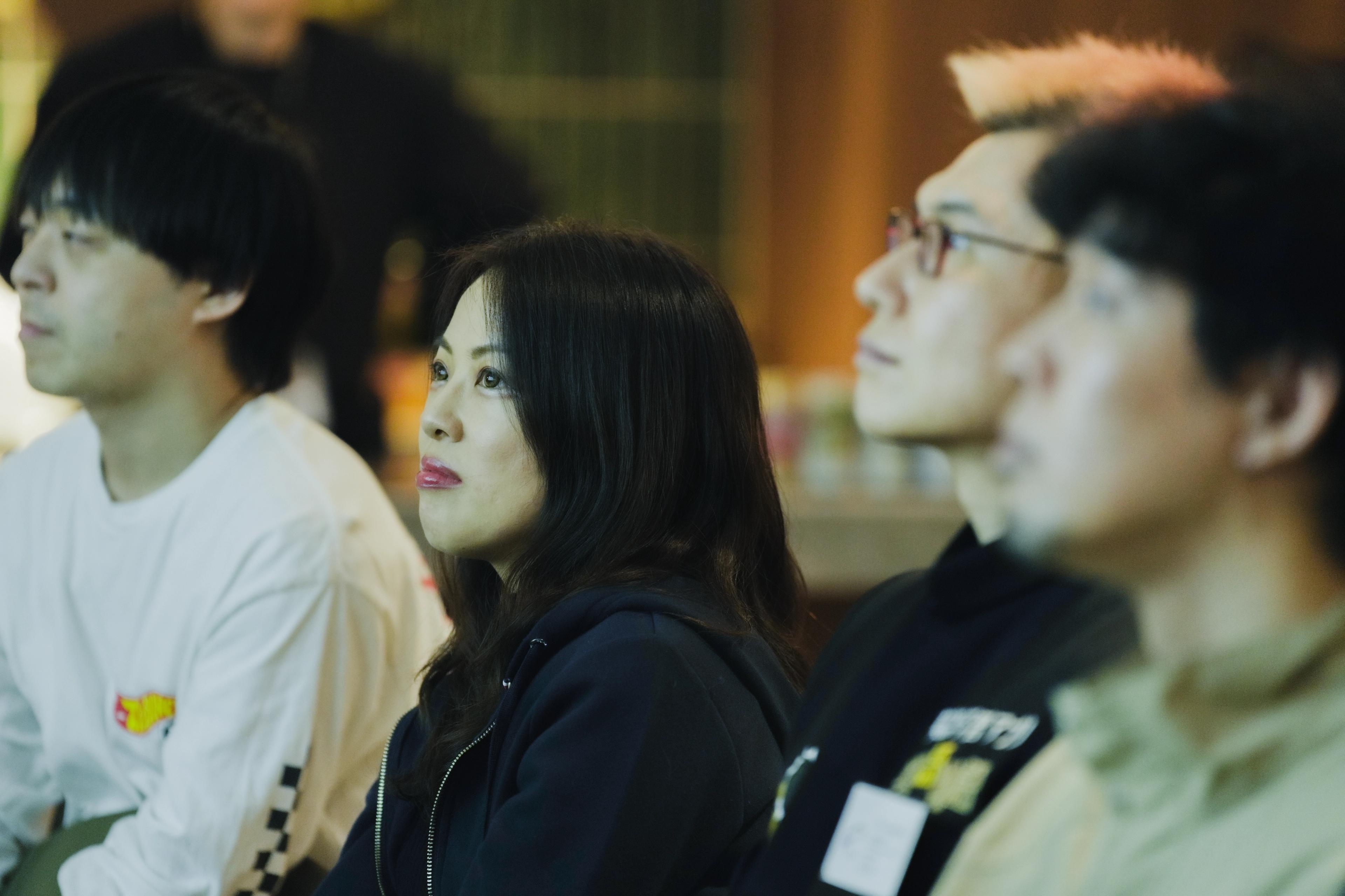 a group of people are sitting in a room watching a presentation .