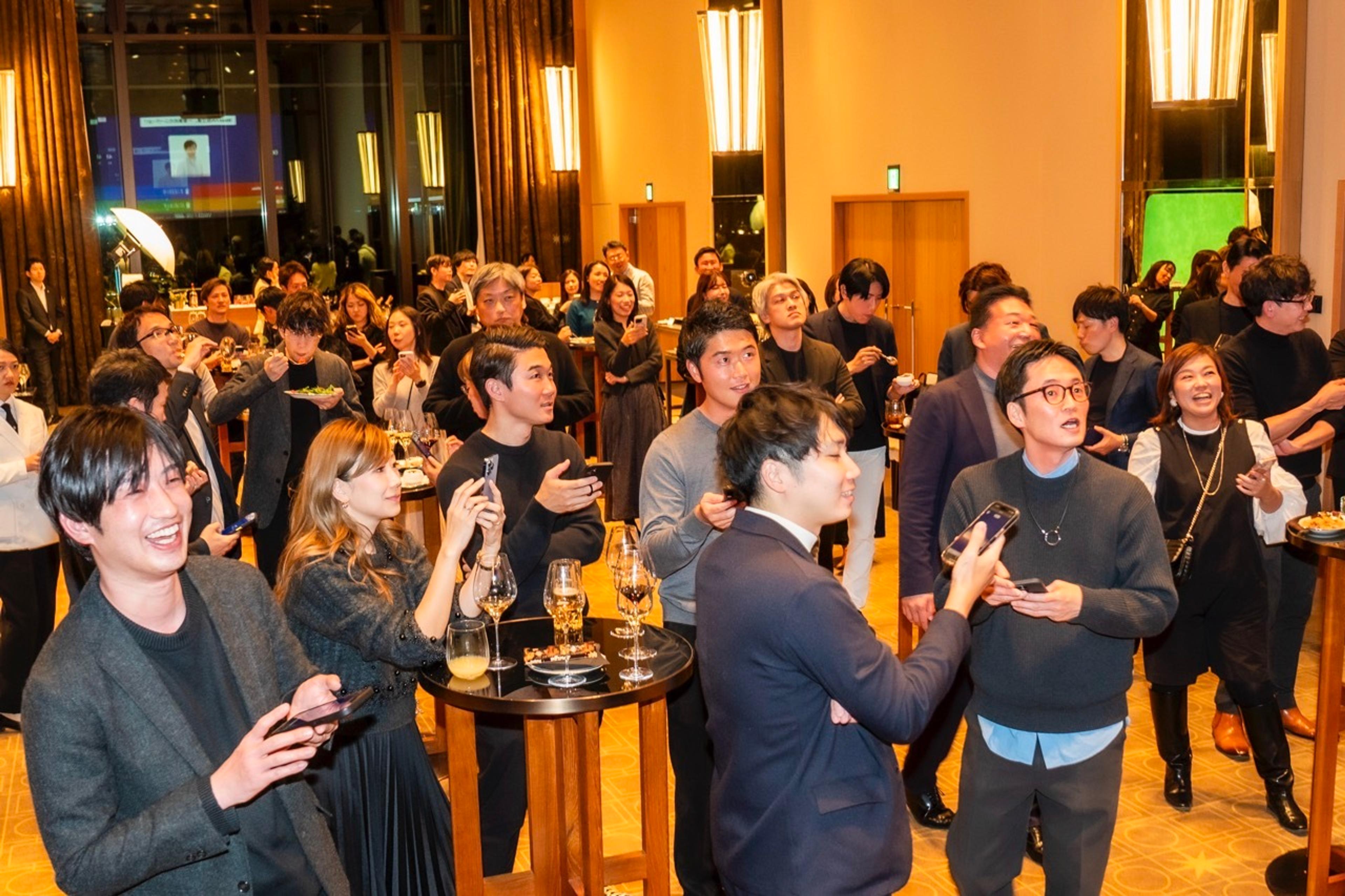 a large group of people are standing around tables at a party .